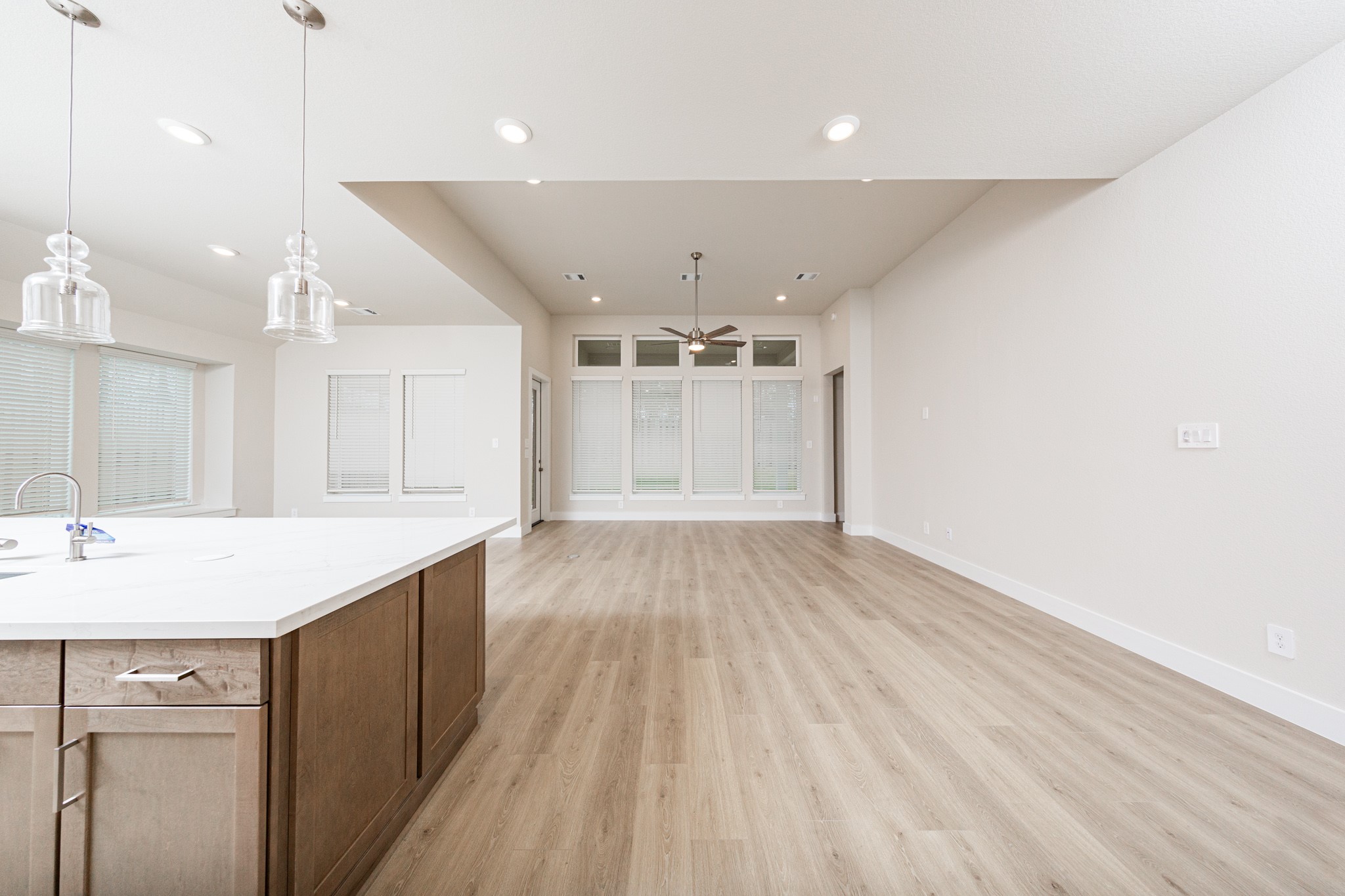 Enjoy the open and airy Family Room, designed for seamless entertaining and showcasing striking architectural details with large tall windows, high ceilings with ceiling fan, recessed lighting, and durable laminate flooring.