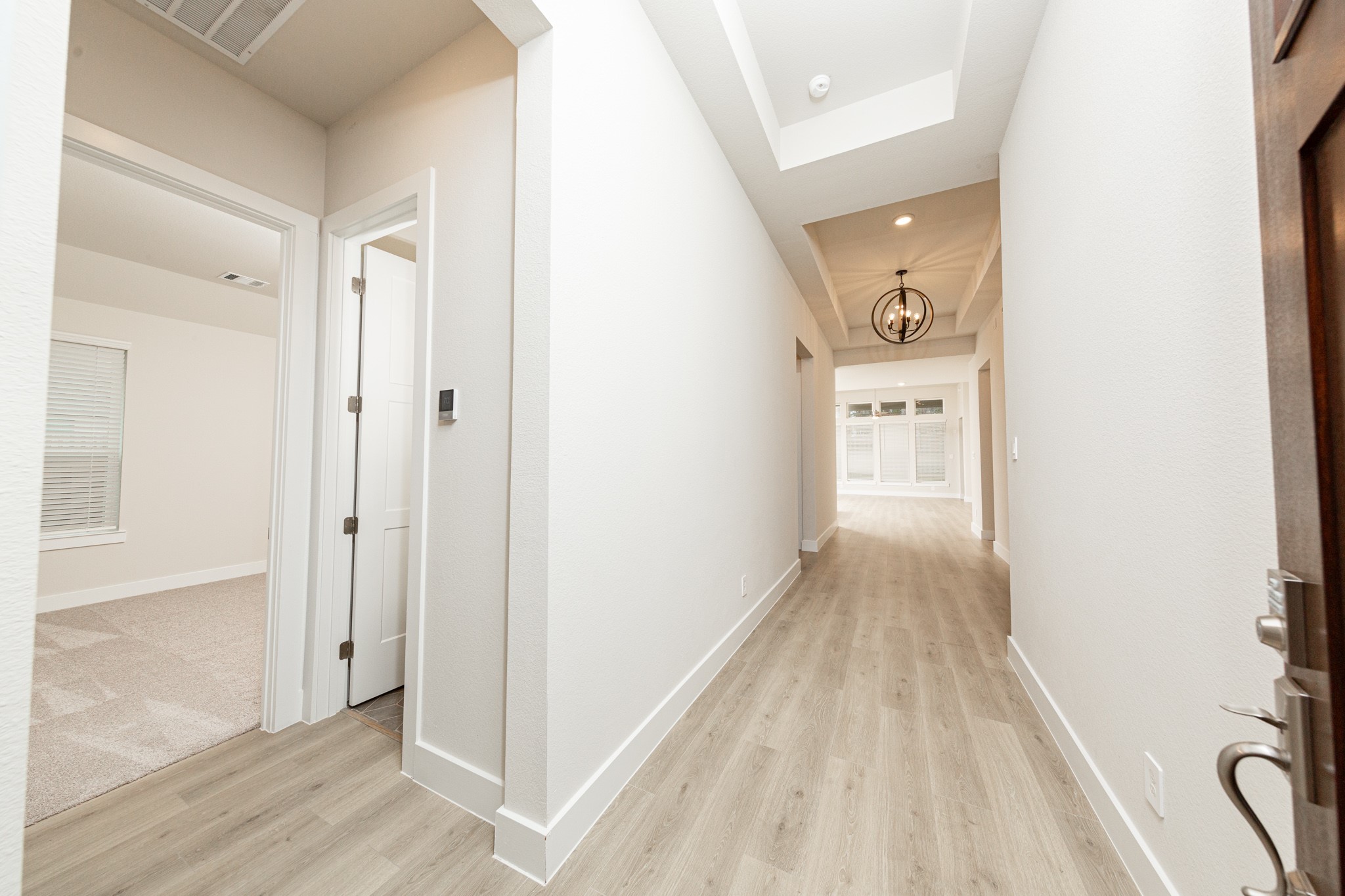 The grand entryway sets an elegant and inviting tone for the home, designed to make a strong first impression. The entryway is illuminated by a stunning black iron orb chandelier, which serves as a significant focal point.