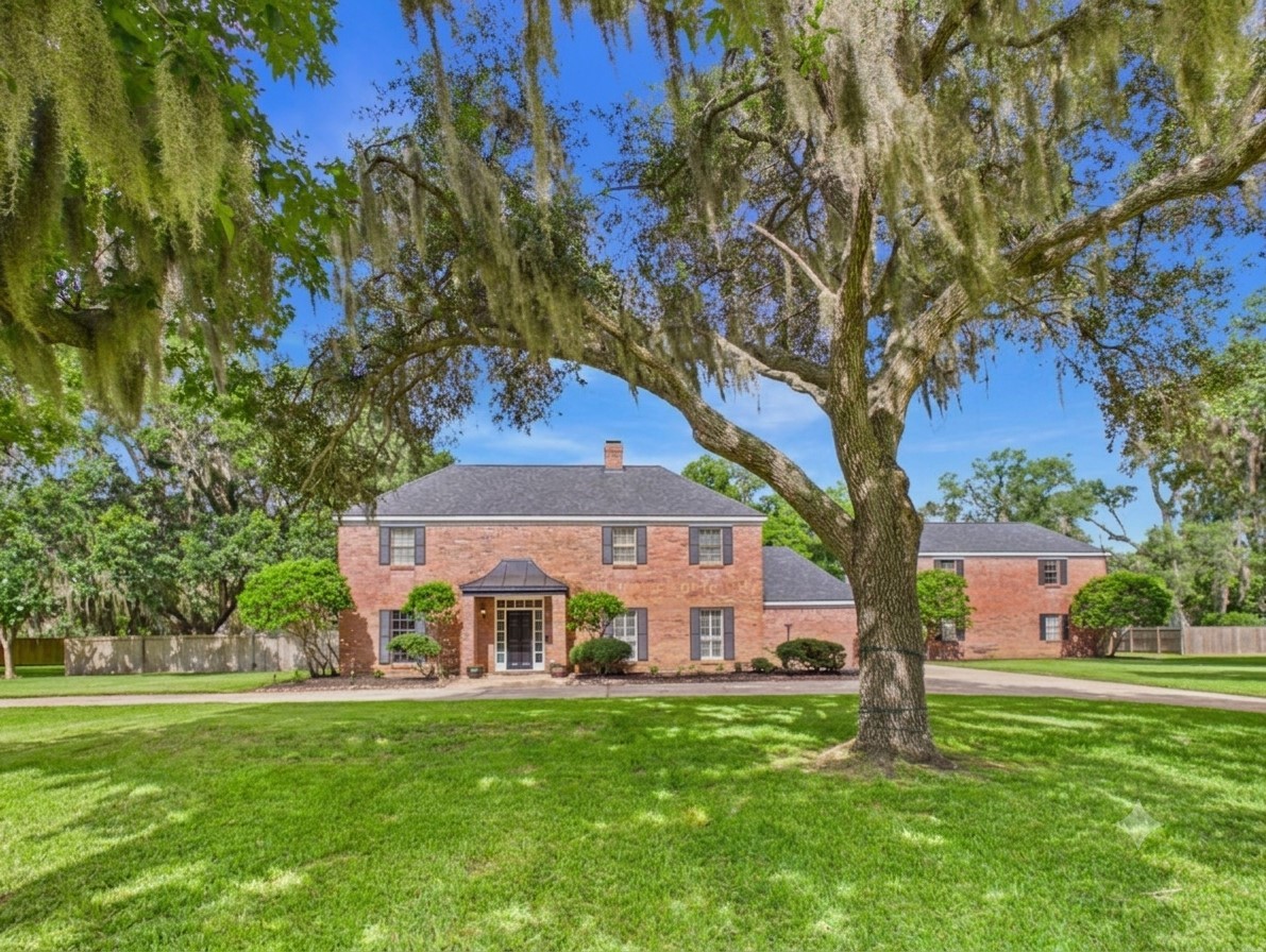Front of the property with live oaks and pecan trees