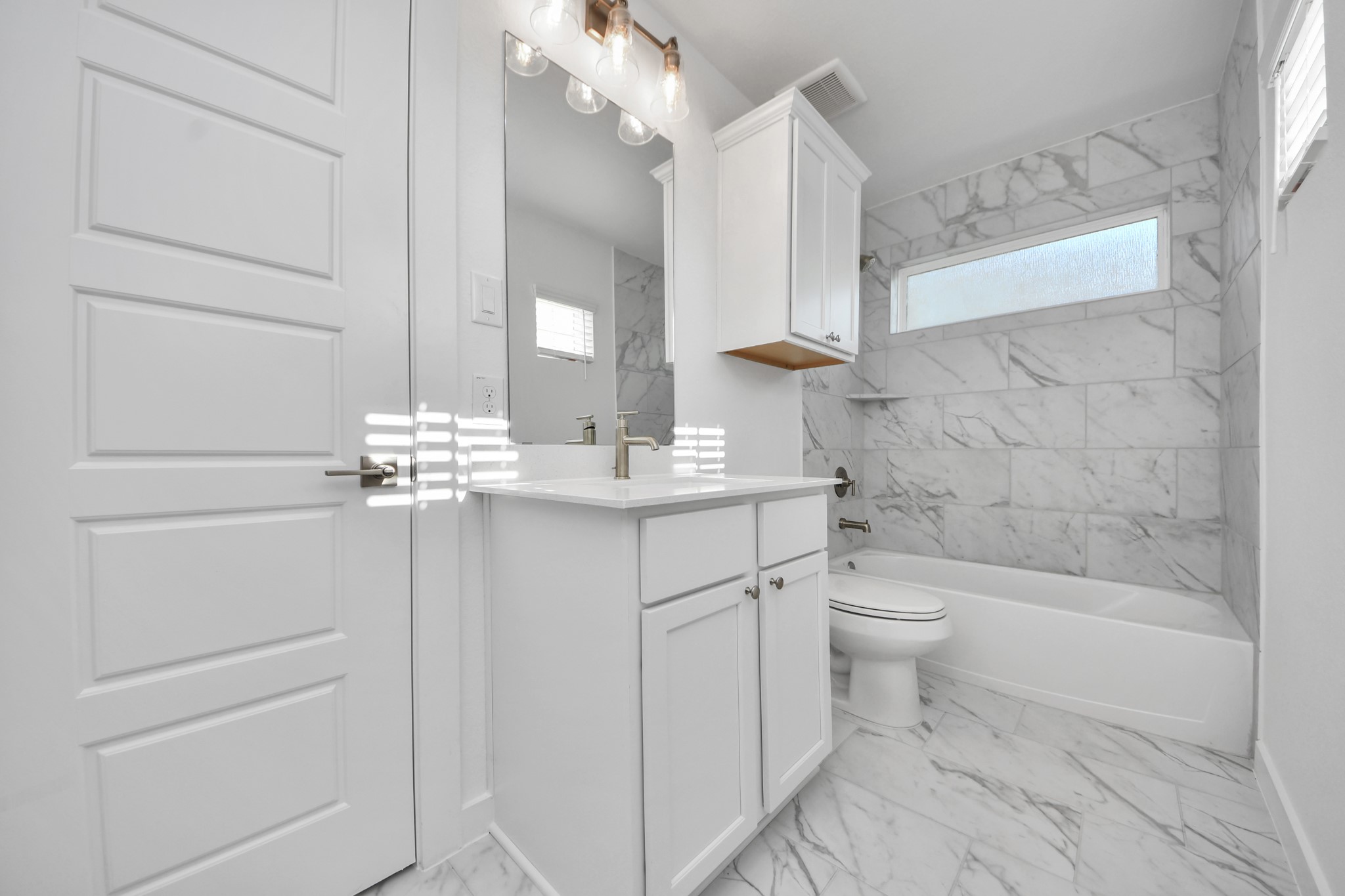 Secondary bath features tile flooring, bath/shower combo with tile surround, light stained wood cabinets, beautiful light countertop.