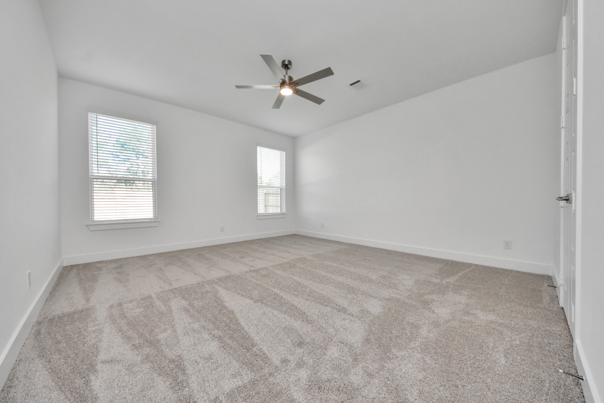 Retreat to the luxurious primary suite, your perfect escape for unwinding after a long day. Located on the first floor, this spacious room features plush carpeting, calming paint tones, high ceilings, and large windows with privacy blinds.