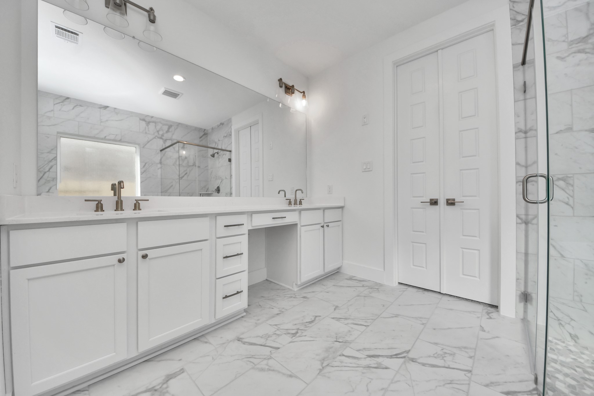 Elevate your daily routine at the elegant vanity, now equipped with double sinks, light countertops, modern hardware, and beautiful recessed lights.