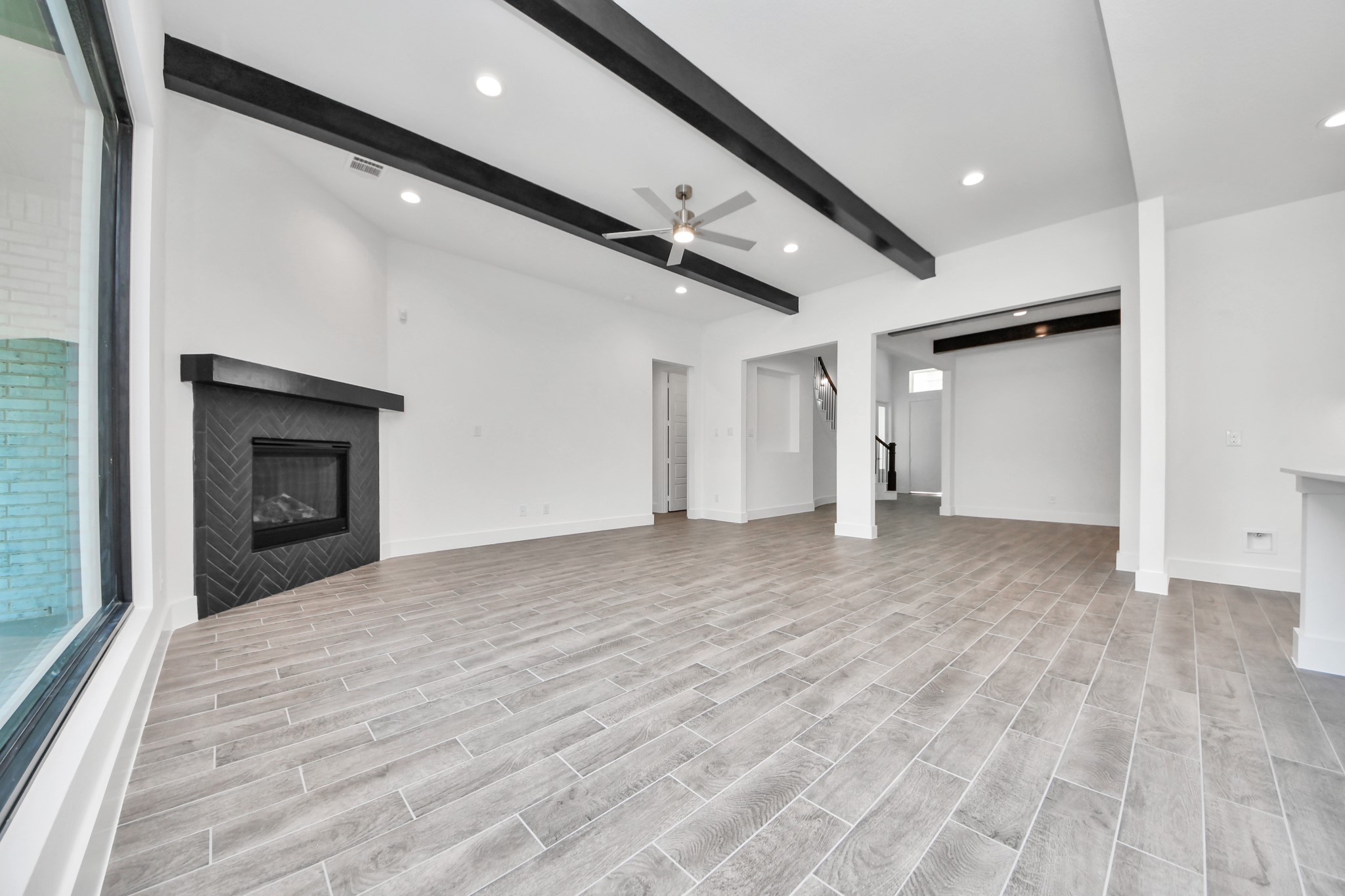 Welcome family and guests to your charming living room! With its high ceilings, recessed lighting, ceiling fan, custom paint, beautiful flooring, and large windows that let in abundant natural light, this room is perfect for gatherings.