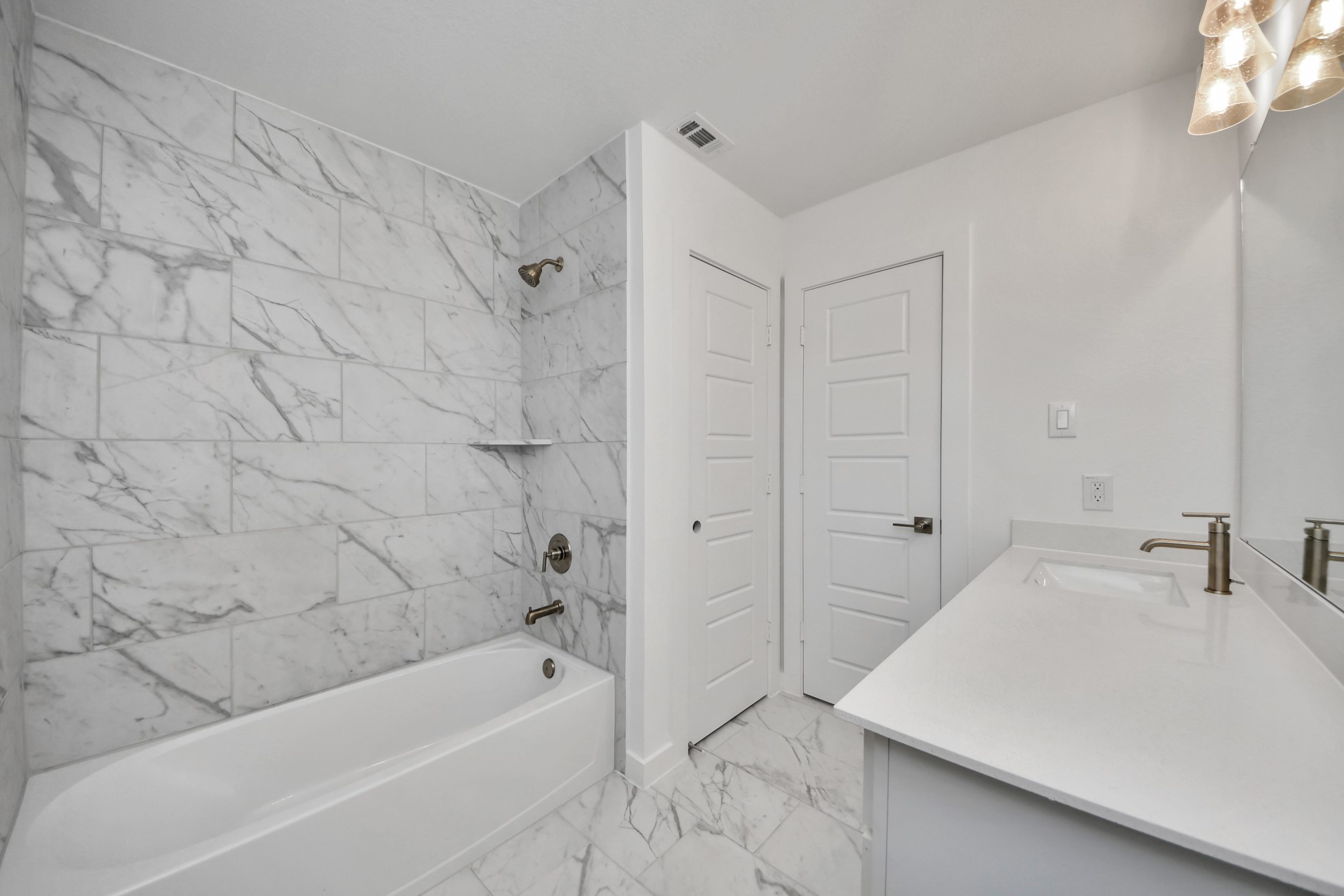 Secondary bath features tile flooring, bath/shower combo with tile surround, light stained wood cabinets, beautiful light countertop.