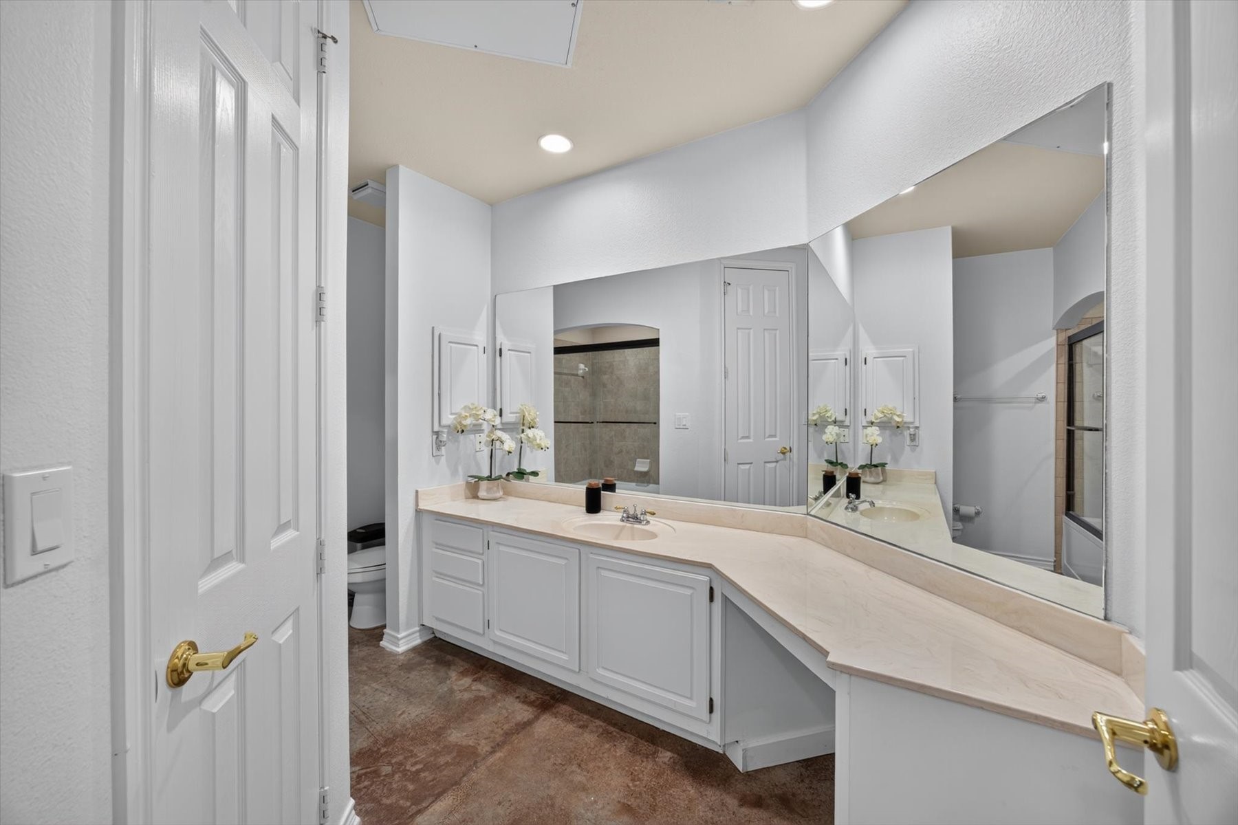 Spacious bathroom featuring a large vanity with ample counter space, elegant mirrors, and sleek white cabinetry, creating a bright and inviting atmosphere.