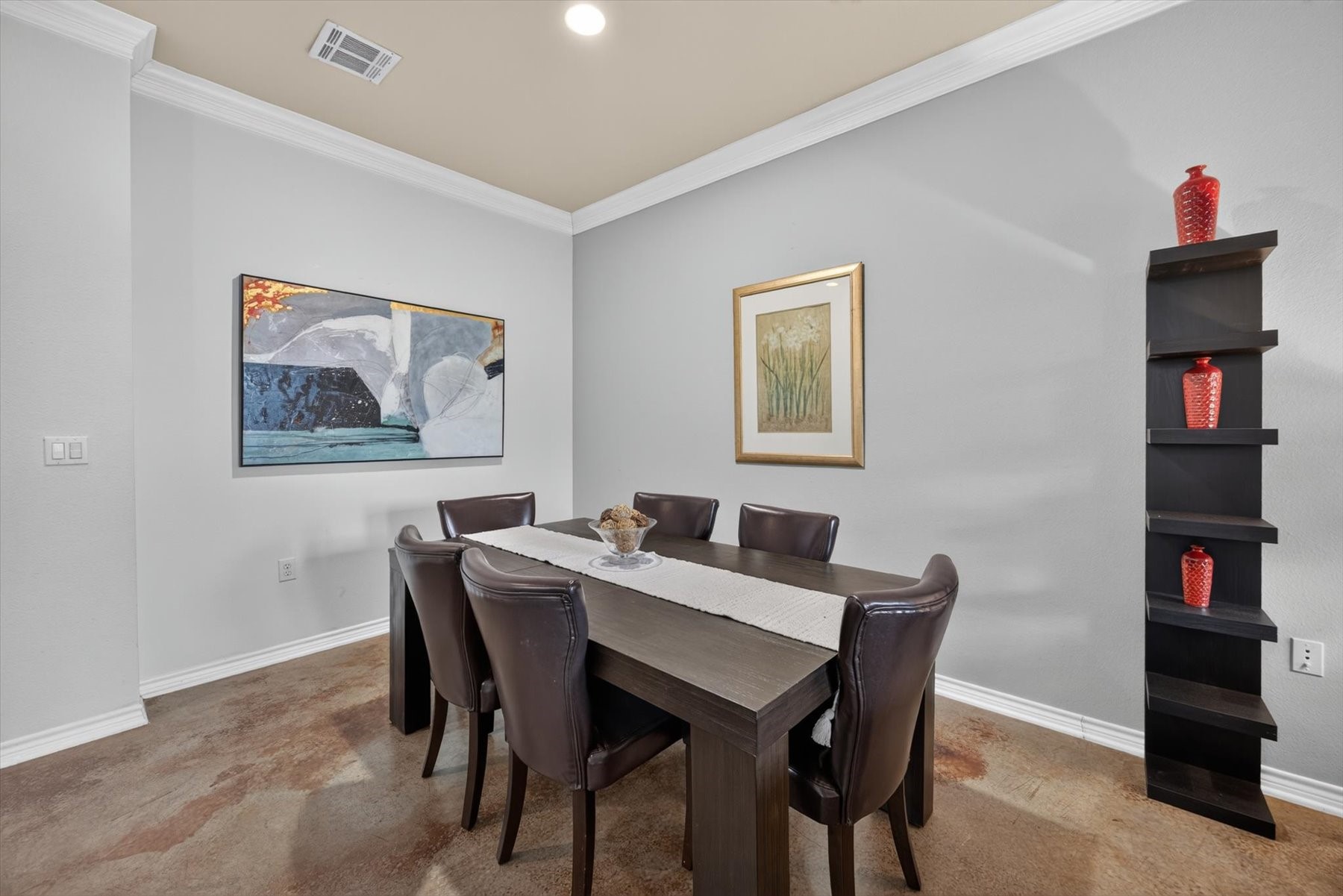 Elegant dining area featuring a modern dark wood table with six leather chairs, accented by tasteful artwork and decorative shelving.