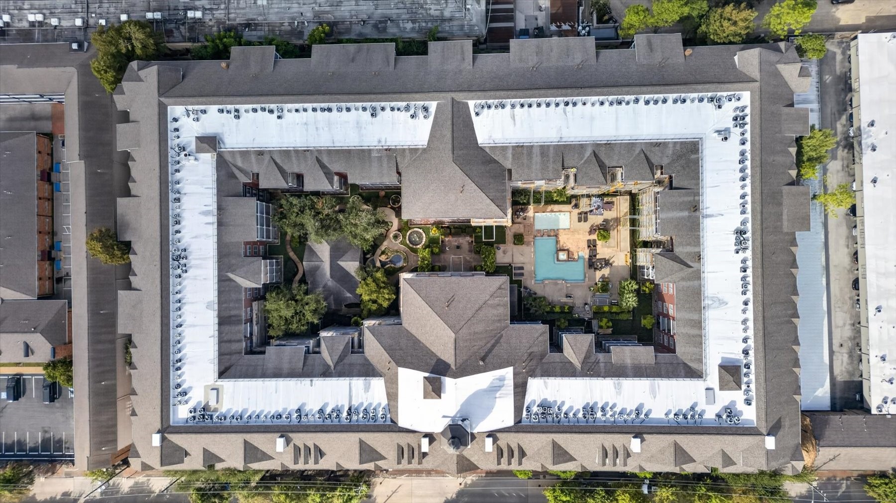 Aerial view of 2400 Mccue Condos featuring a central courtyard with lush greenery and a sparkling pool, offering a serene and private urban oasis.