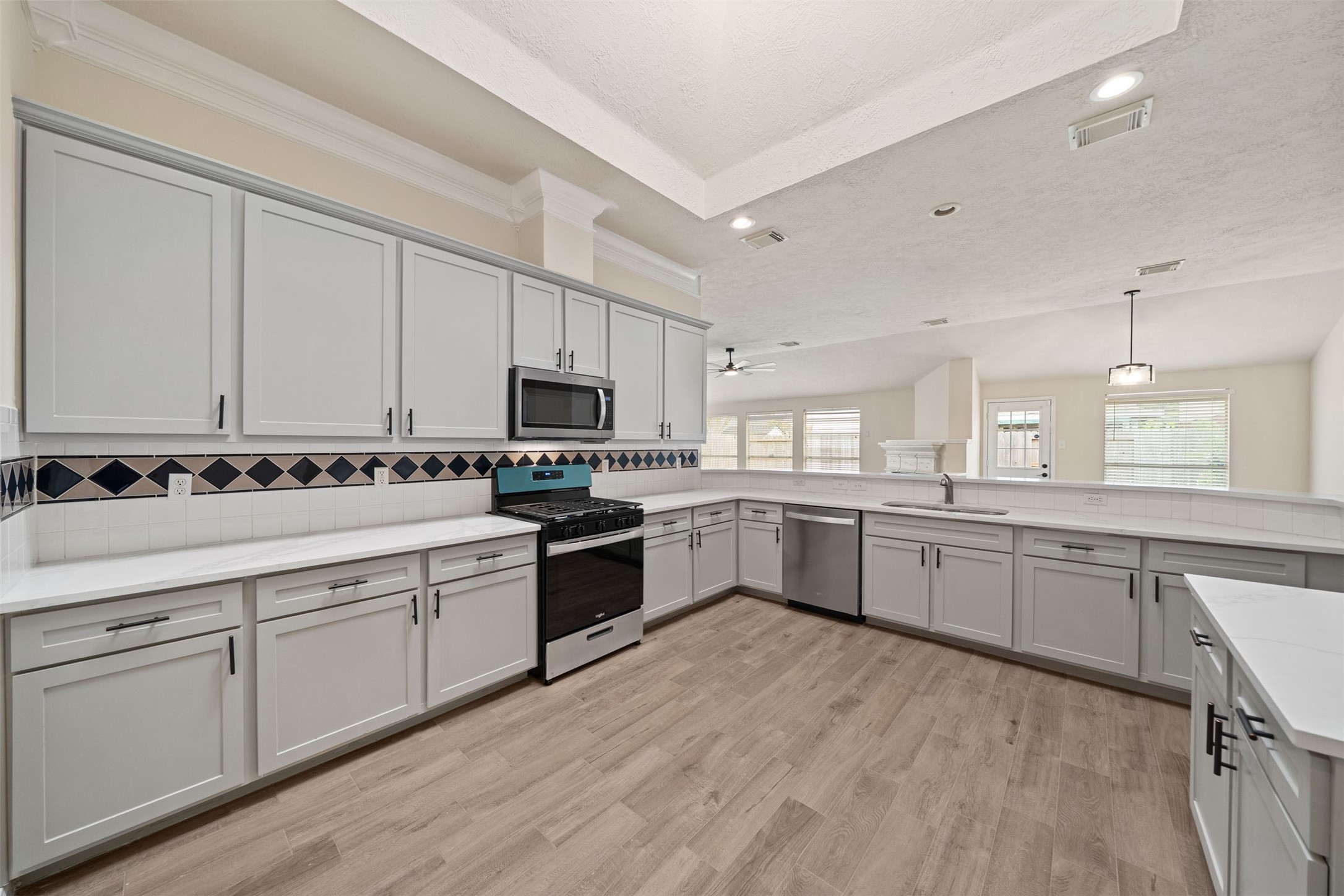 Oversized kitchen featuring an elegant tile backsplash, wood-style flooring, and a skylight