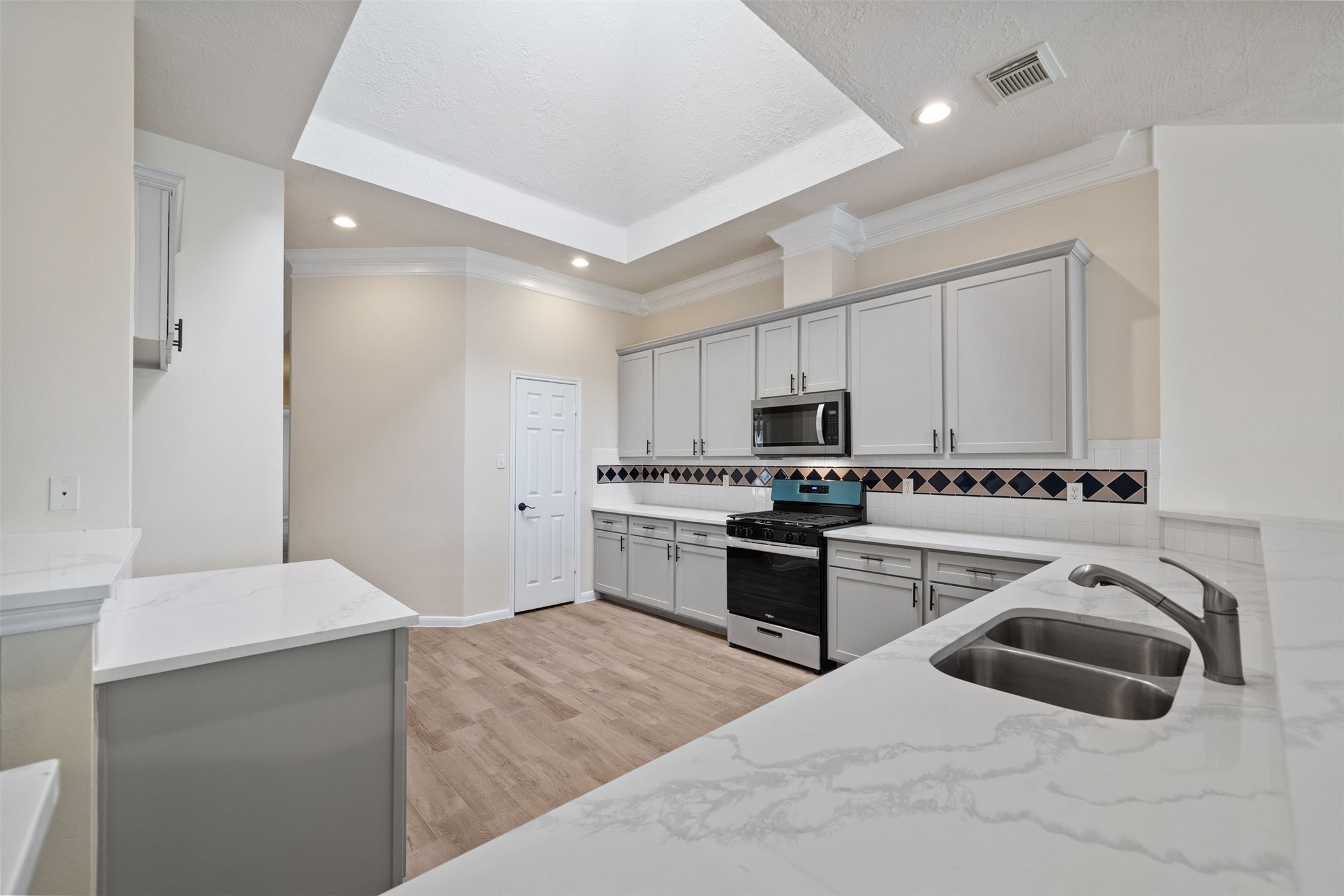 Elegant kitchen space with crown molding and ample lighting, perfect for culinary enthusiasts.