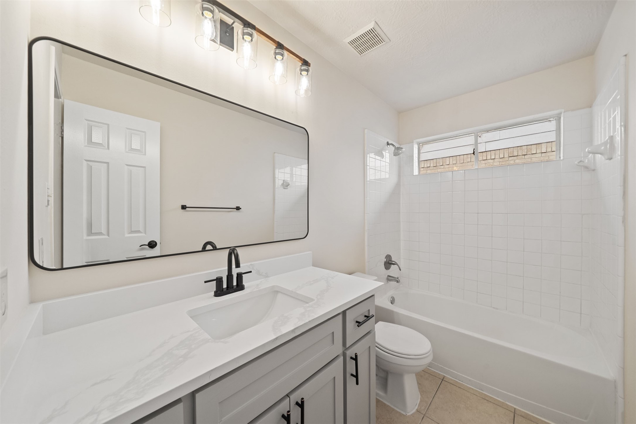 Bright and modern 2nd full bathroom featuring a sleek vanity with a Quartz countertop, large mirror, and a classic tub-shower combo.