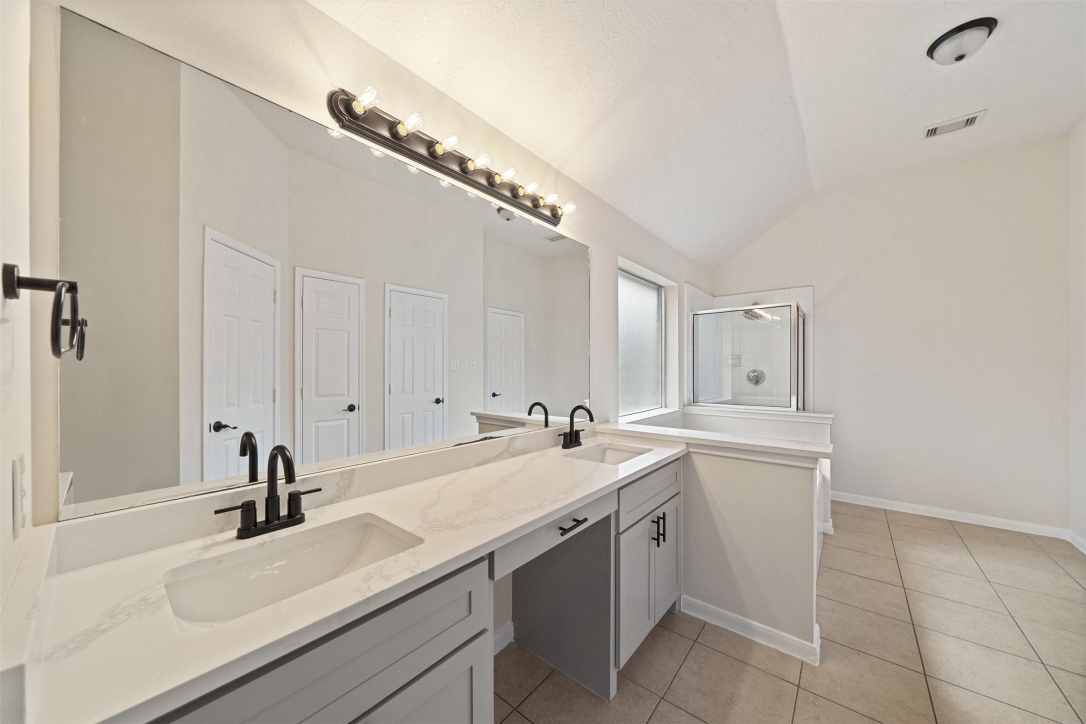 Renovated primary bathroom with modern dual sinks, elegant fixtures, a large mirror, and a glass-enclosed shower, offering a sleek and functional design. Renovated primary bathroom with modern dual sinks, elegant fixtures, a large mirror, and a glass-enclosed shower, offering a sleek and functional design.