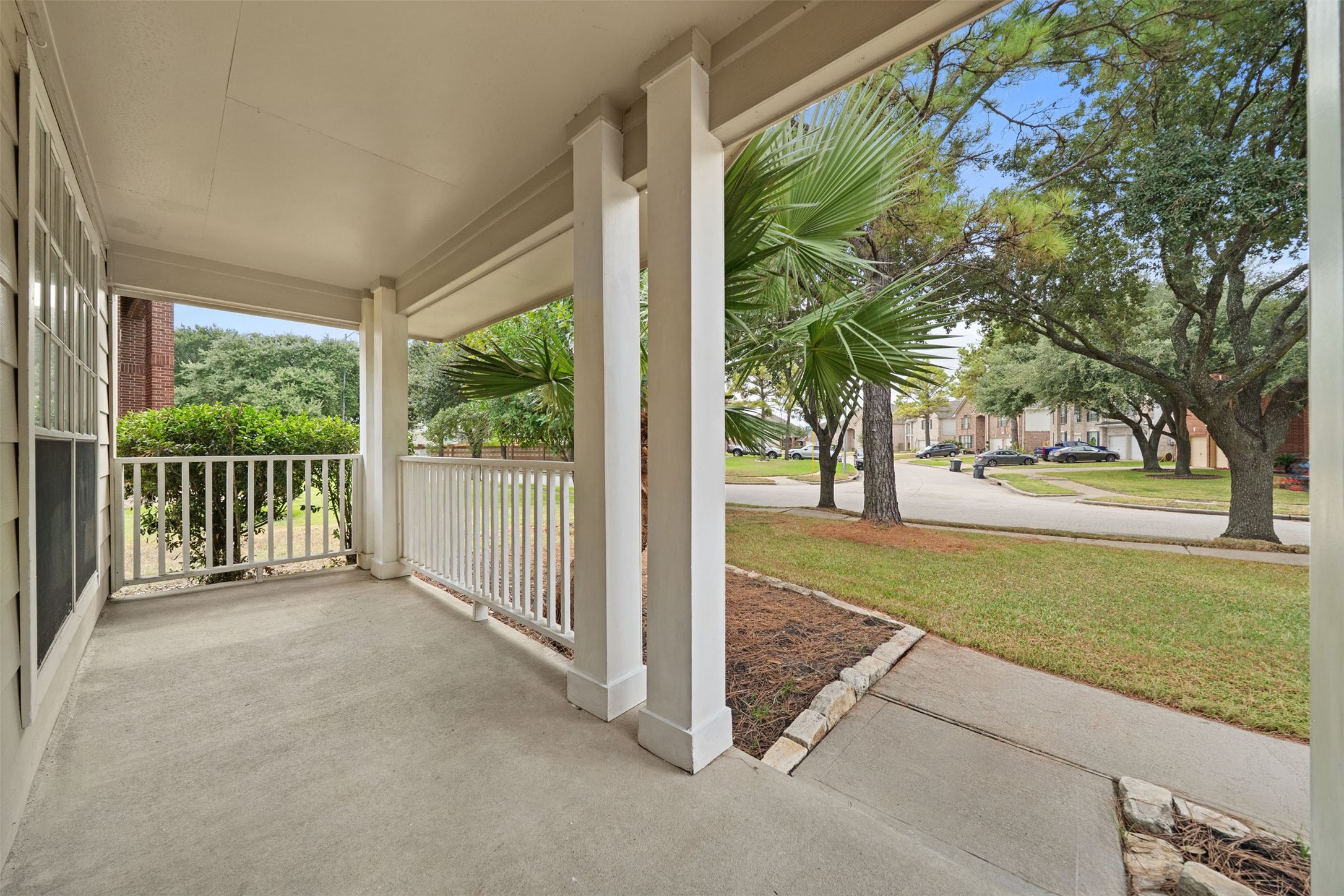 Charming front porch with classic railing overlooks a serene neighborhood street, surrounded by lush greenery and mature trees. Charming front porch with classic railing overlooks a serene neighborhood street, surrounded by lush greenery and mature trees.