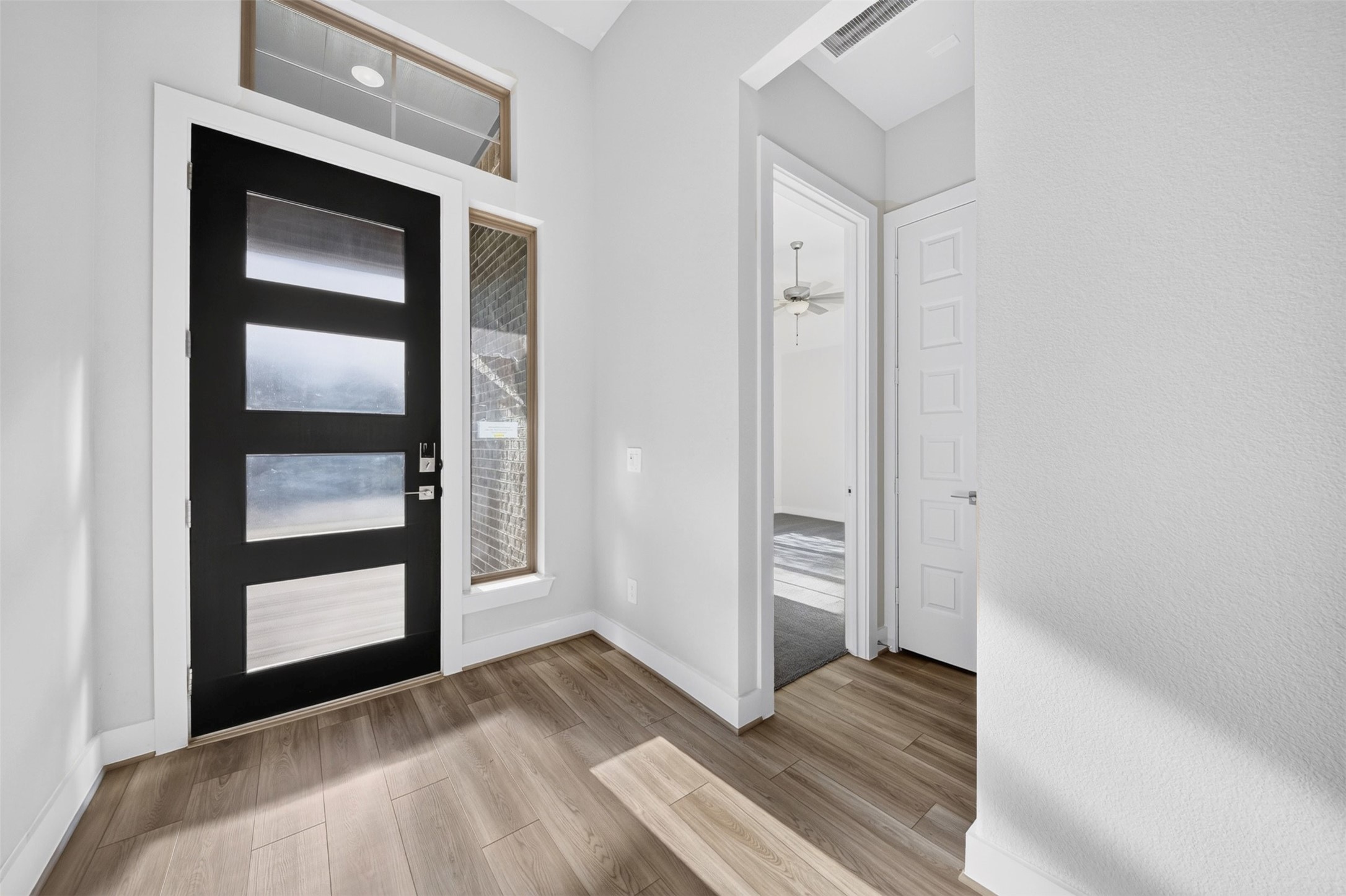 Front Entryway: Impressive entryway featuring soaring ceilings, a contemporary front door with glass accents, beautiful wood-look flooring, and abundant natural light that creates an inviting first impression.
