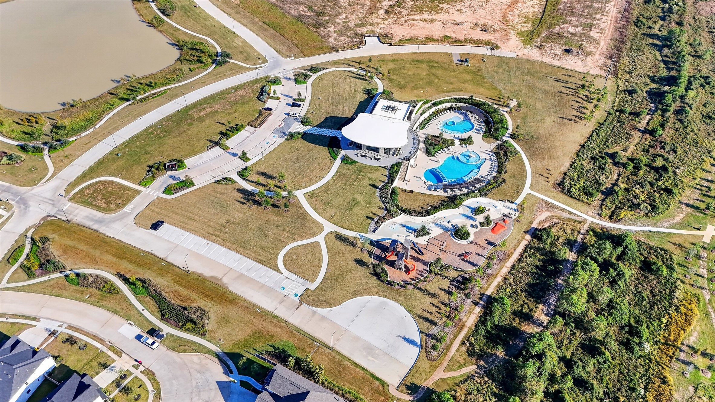 The Grand Prairie  Aerial Community View: Discover exceptional community amenities featuring resort-style pools, a beautiful clubhouse, playgrounds, and scenic walking trails surrounded by landscaped green spaces.