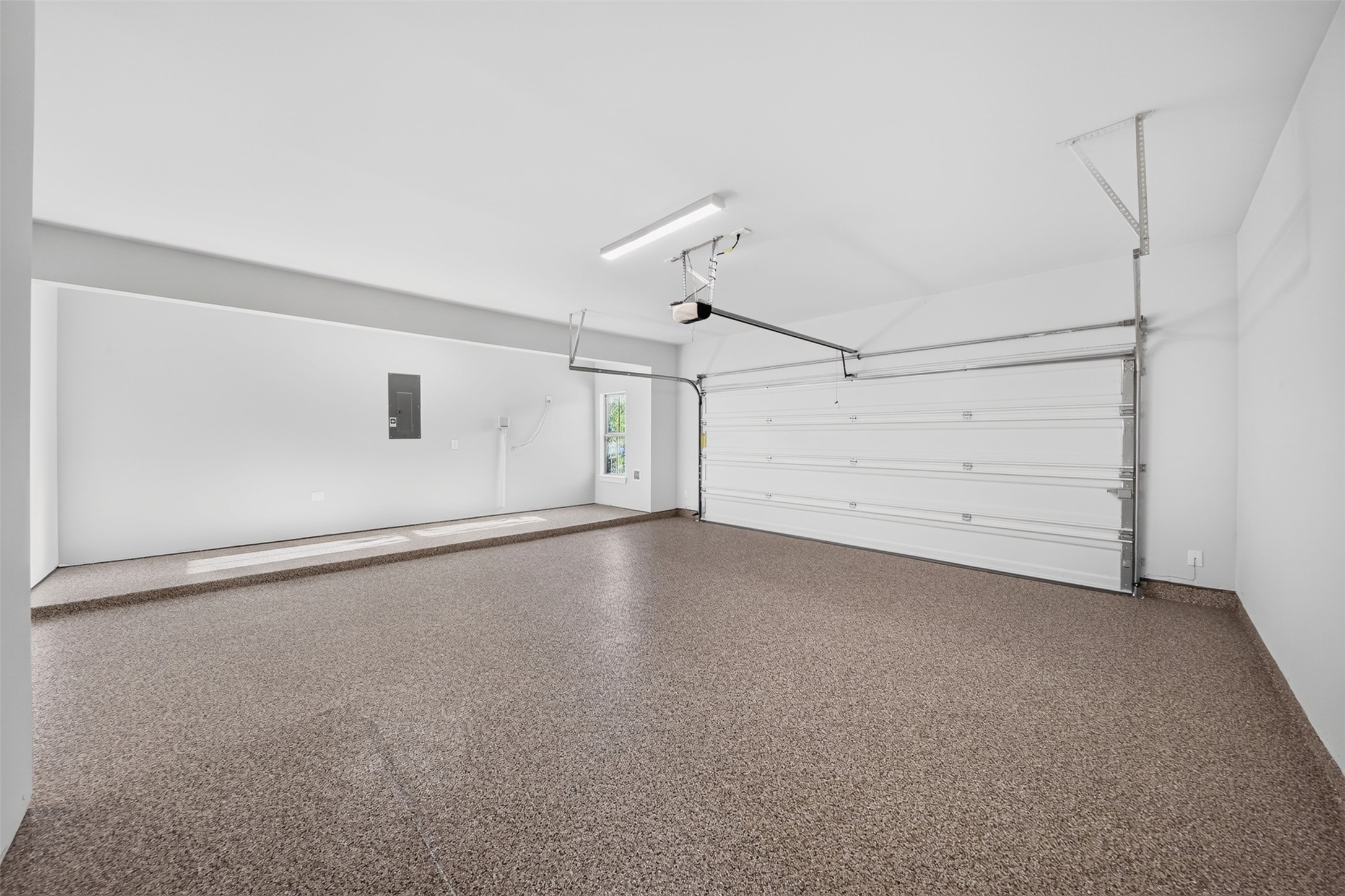 Three-Car Garage: Spacious three-car tandem garage featuring a finished floor, bright interior, and ample room for parking, storage, and everyday convenience.