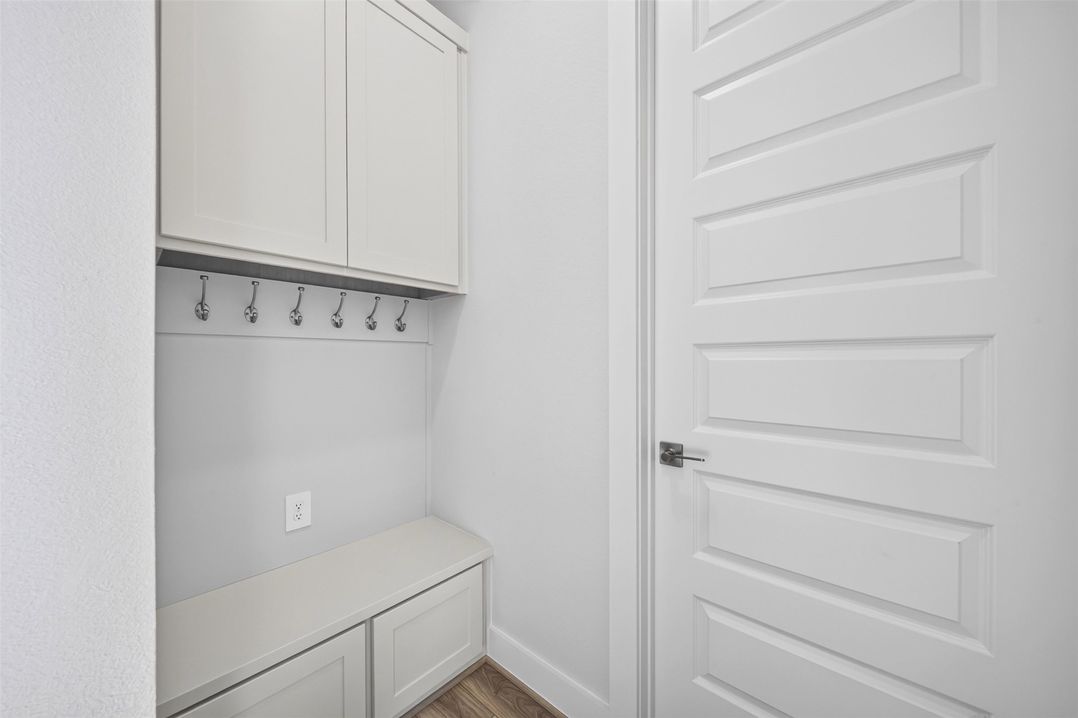 11. Built-In Storage & Drop Zone: Thoughtfully designed storage area featuring built-in cabinetry, a convenient bench, and wall hooks, providing an organized space for everyday essentials.