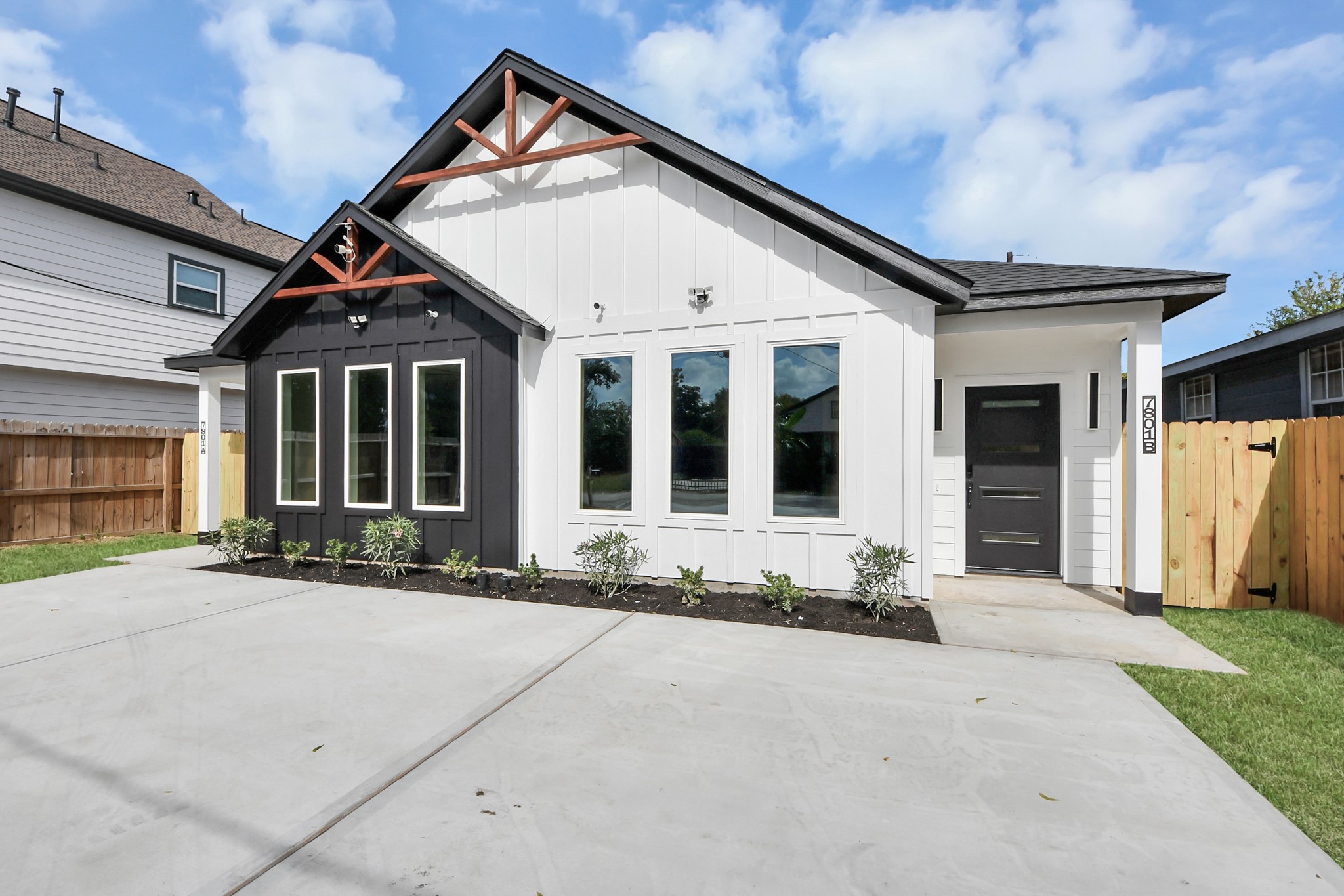 Chic modern home with a striking black-and-white exterior, large windows, and a welcoming front porch.