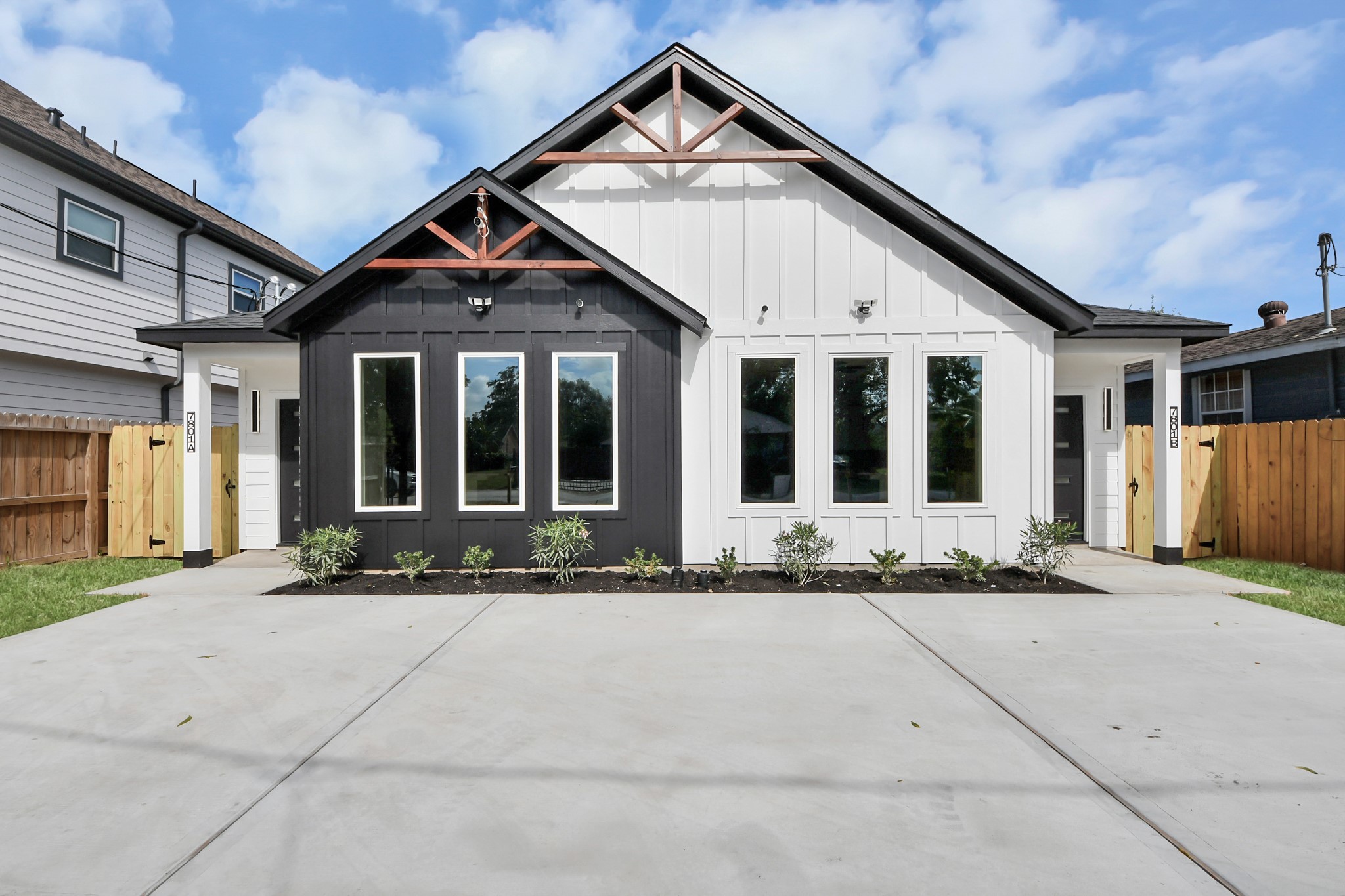 Modern duplex with striking black and white exterior, featuring large windows and a clean, spacious driveway.