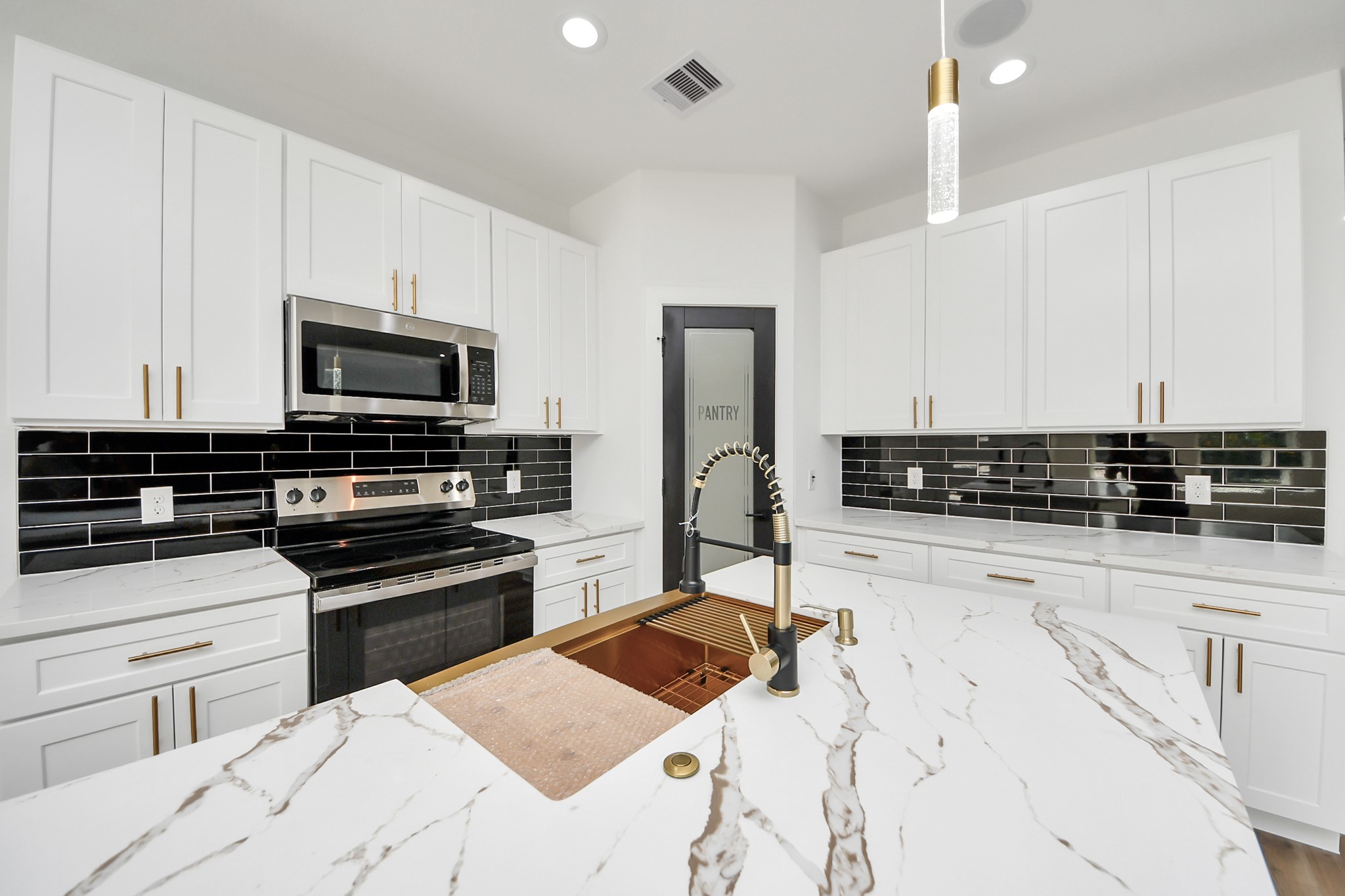 Sleek and modern kitchen featuring elegant white cabinetry, striking black subway tile backsplash, and luxurious marble countertops, complete with a high-end stainless steel appliance suite.