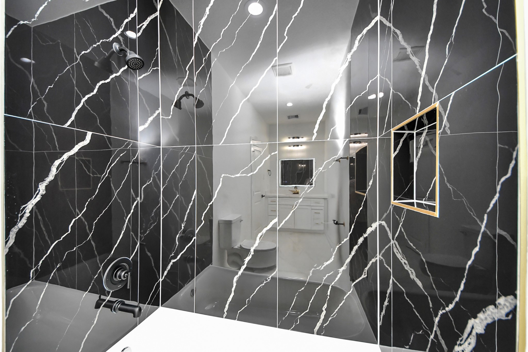 Luxurious bathroom featuring elegant black marble tiles with striking white veining, complemented by modern fixtures for a sophisticated look.
