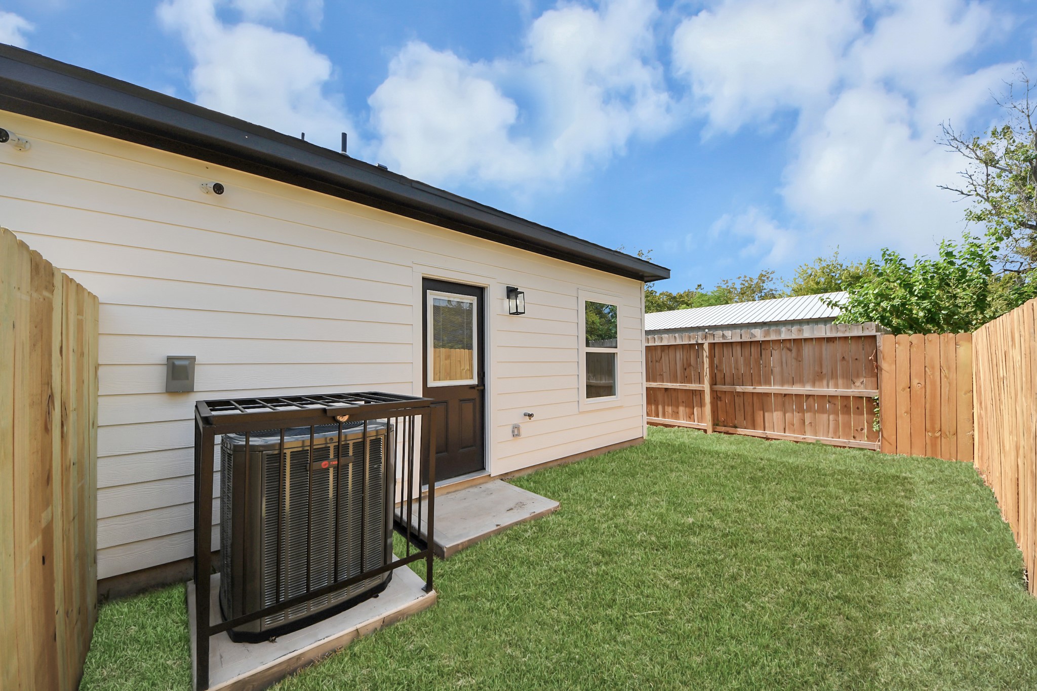 Charming backyard with a neatly maintained lawn, privacy fence, and convenient backdoor access.