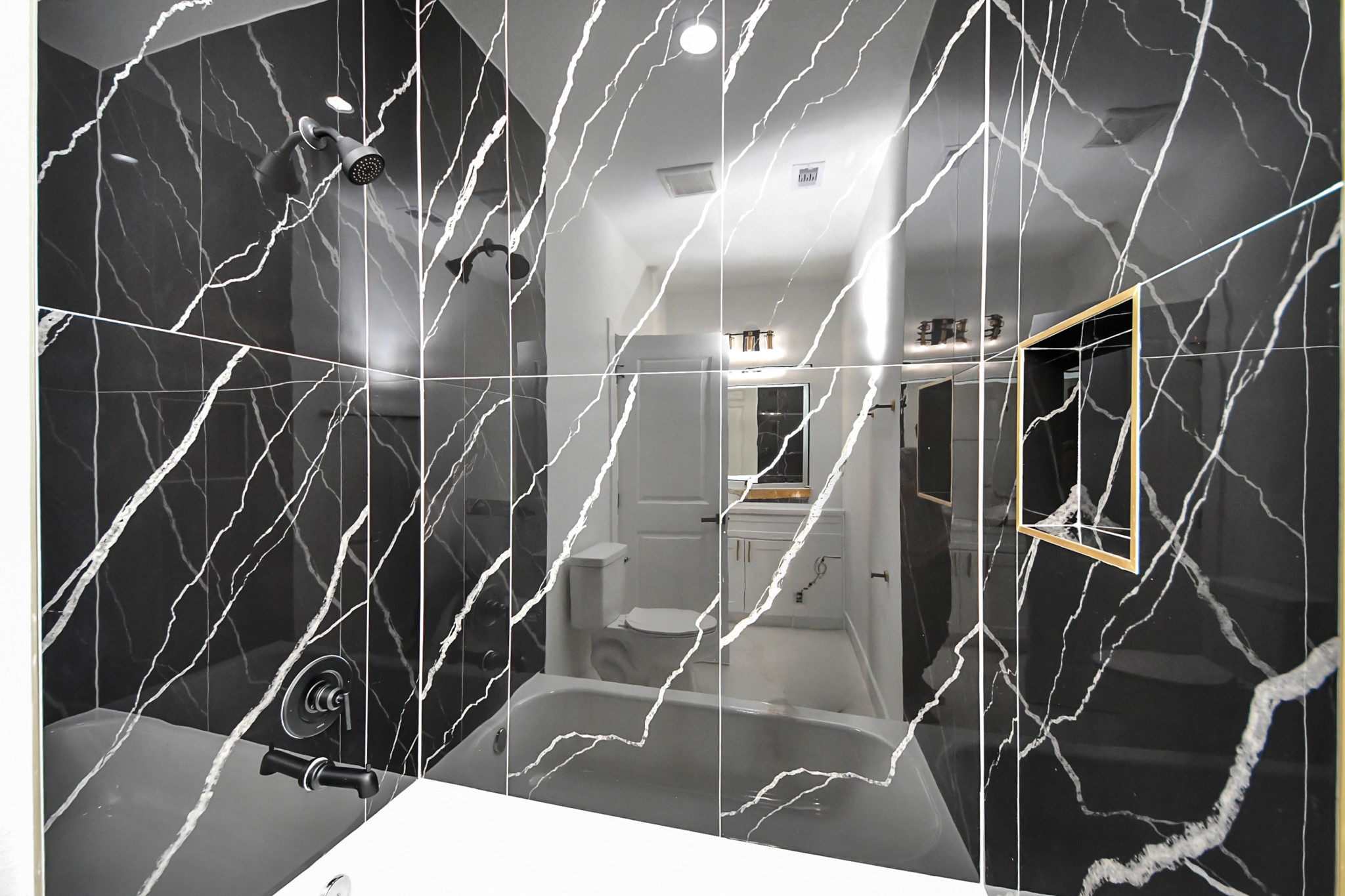 Elegant bathroom featuring striking black marble tiles with white veining, a modern showerhead, and sleek fixtures, creating a luxurious and contemporary feel.