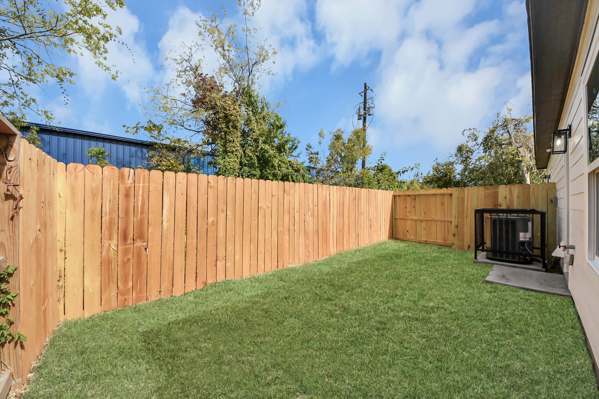 A private backyard oasis featuring a lush green lawn and a wooden privacy fence, perfect for relaxation and outdoor activities.