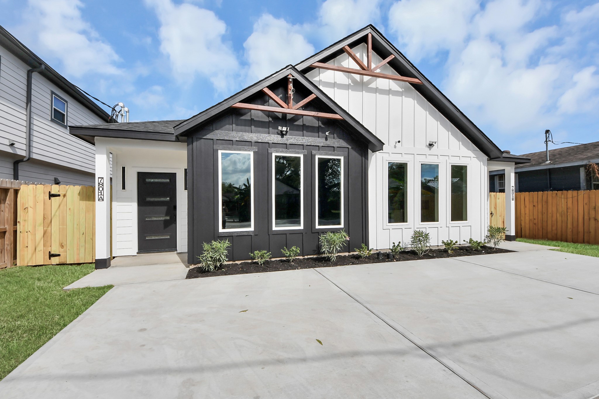 Chic and modern, this home features a striking black and white exterior with a welcoming front porch, large windows, and a spacious driveway, offering great curb appeal.