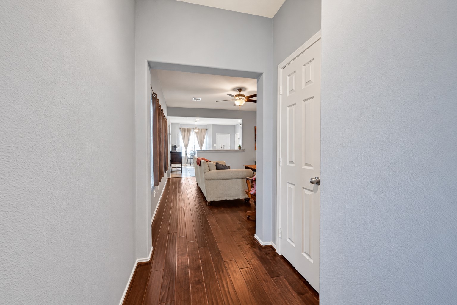 Interior view of the entryway continuing the wood flooring, and neutral tone white doors matching with the walls to give a clean minimalist look.