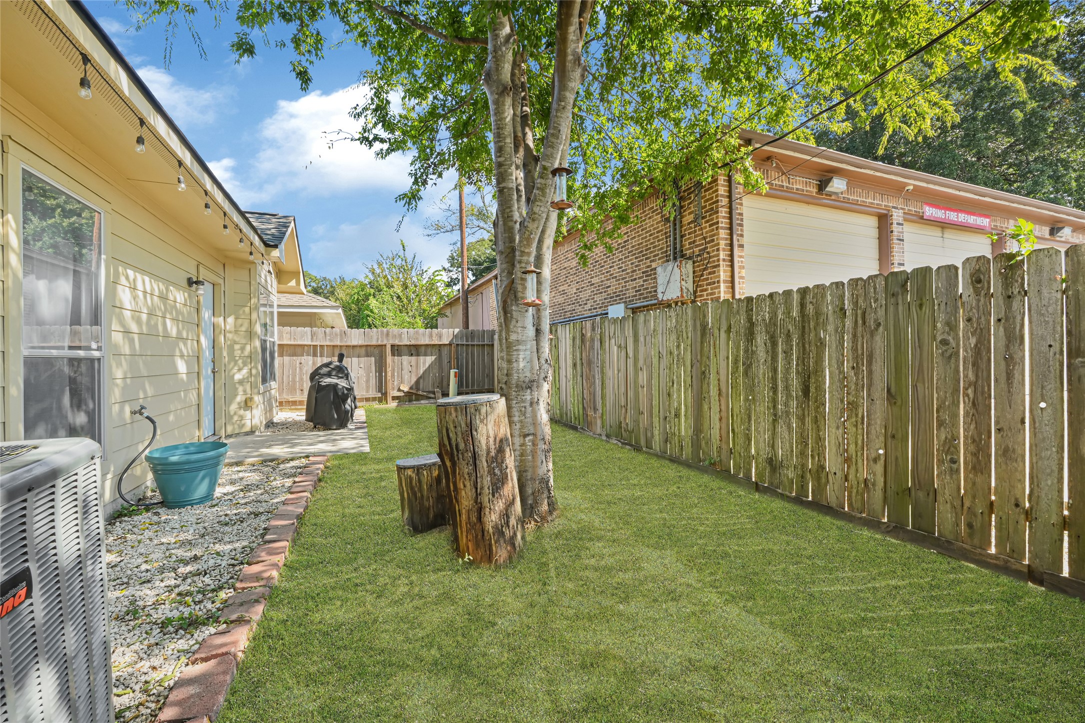 Charming backyard with a lush lawn, shaded by mature trees, and perfect for relaxation, featuring a tidy patio area ideal for outdoor grilling.