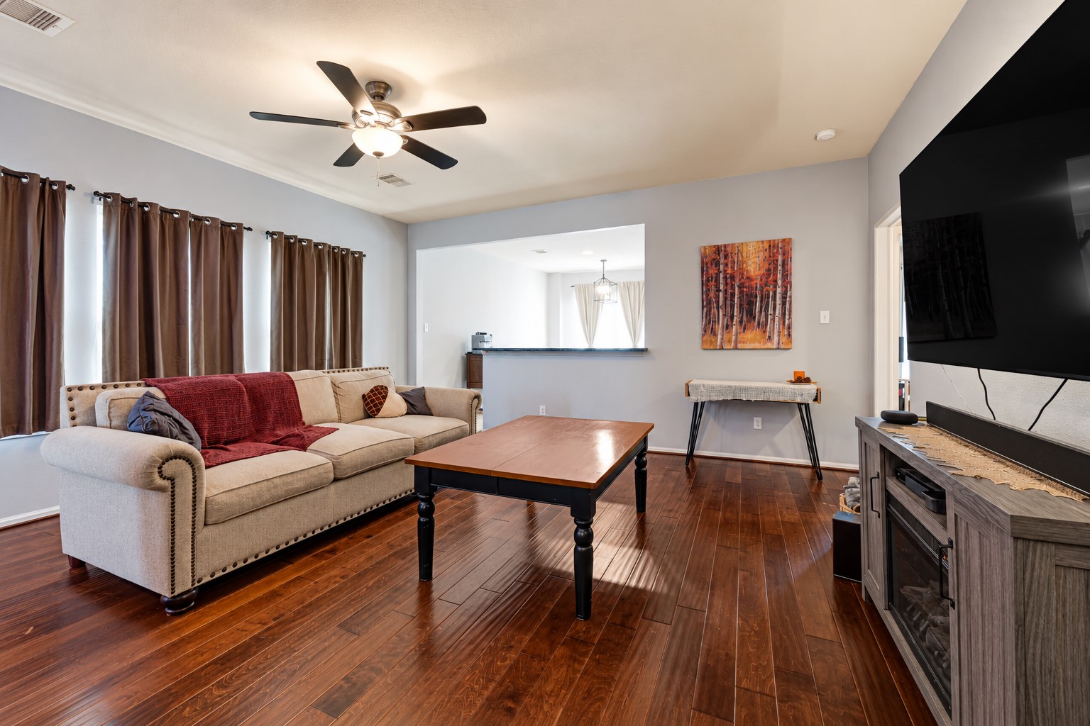 Spacious living area with elegant hardwood floors, a cozy sectional sofa, and a modern ceiling fan, perfect for relaxation and entertainment. Spacious living area with elegant hardwood floors, a cozy sectional sofa, and a modern ceiling fan, perfect for relaxation and entertainment.