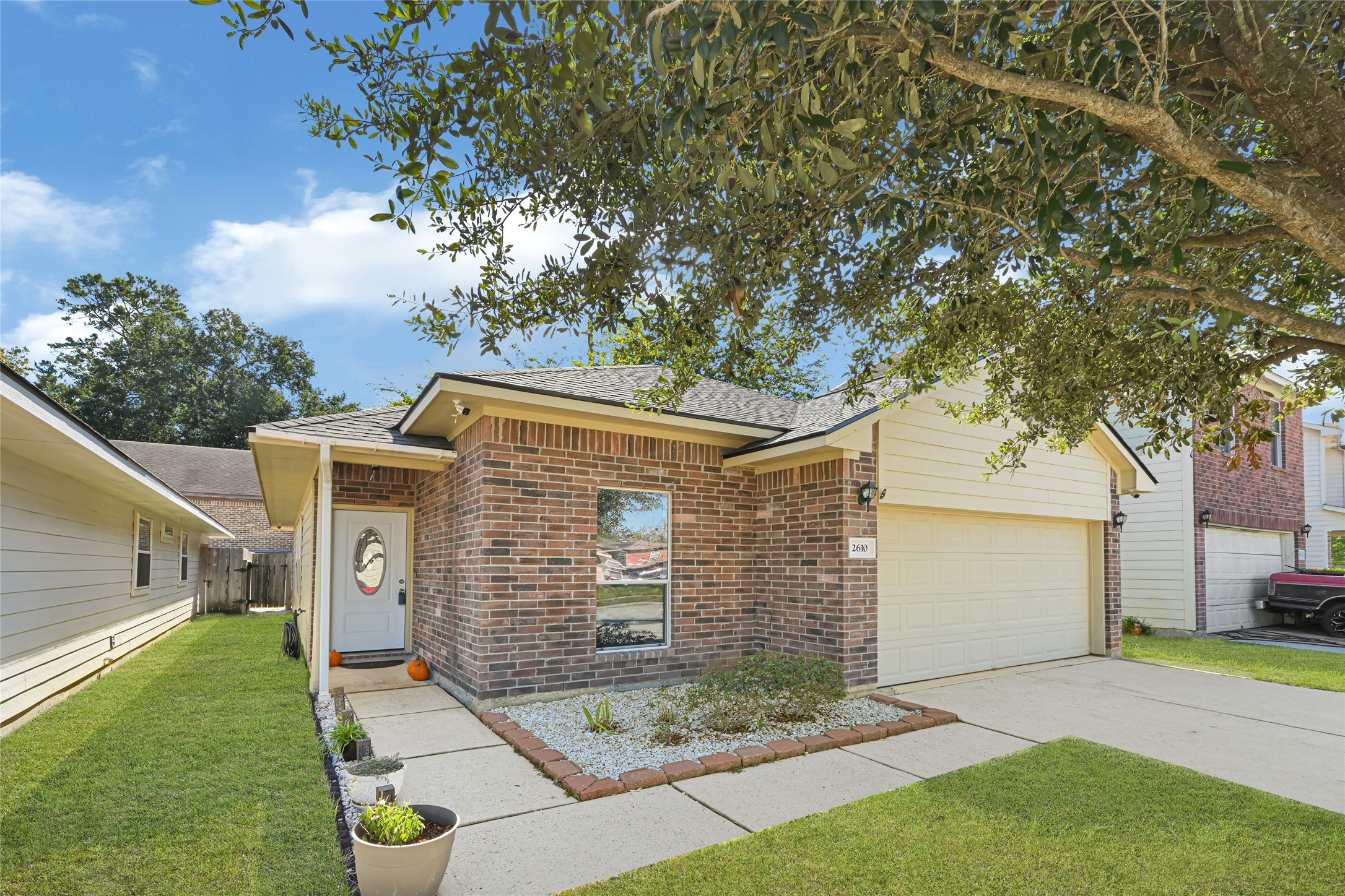 Charming brick home with a welcoming front entrance, manicured lawn, and attached garage, nestled in a serene neighborhood.
