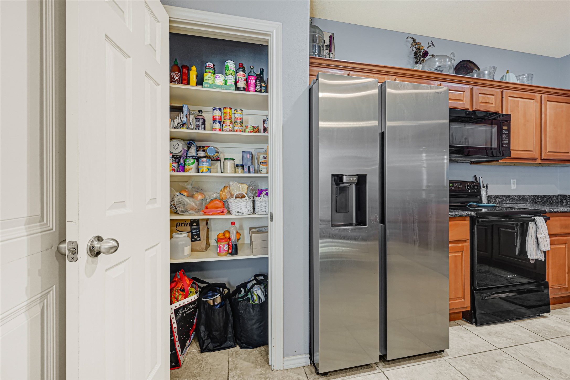A six later pantry for plenty of storage of dry goods alongside a large steel refrigerator that is to be included in the sale.