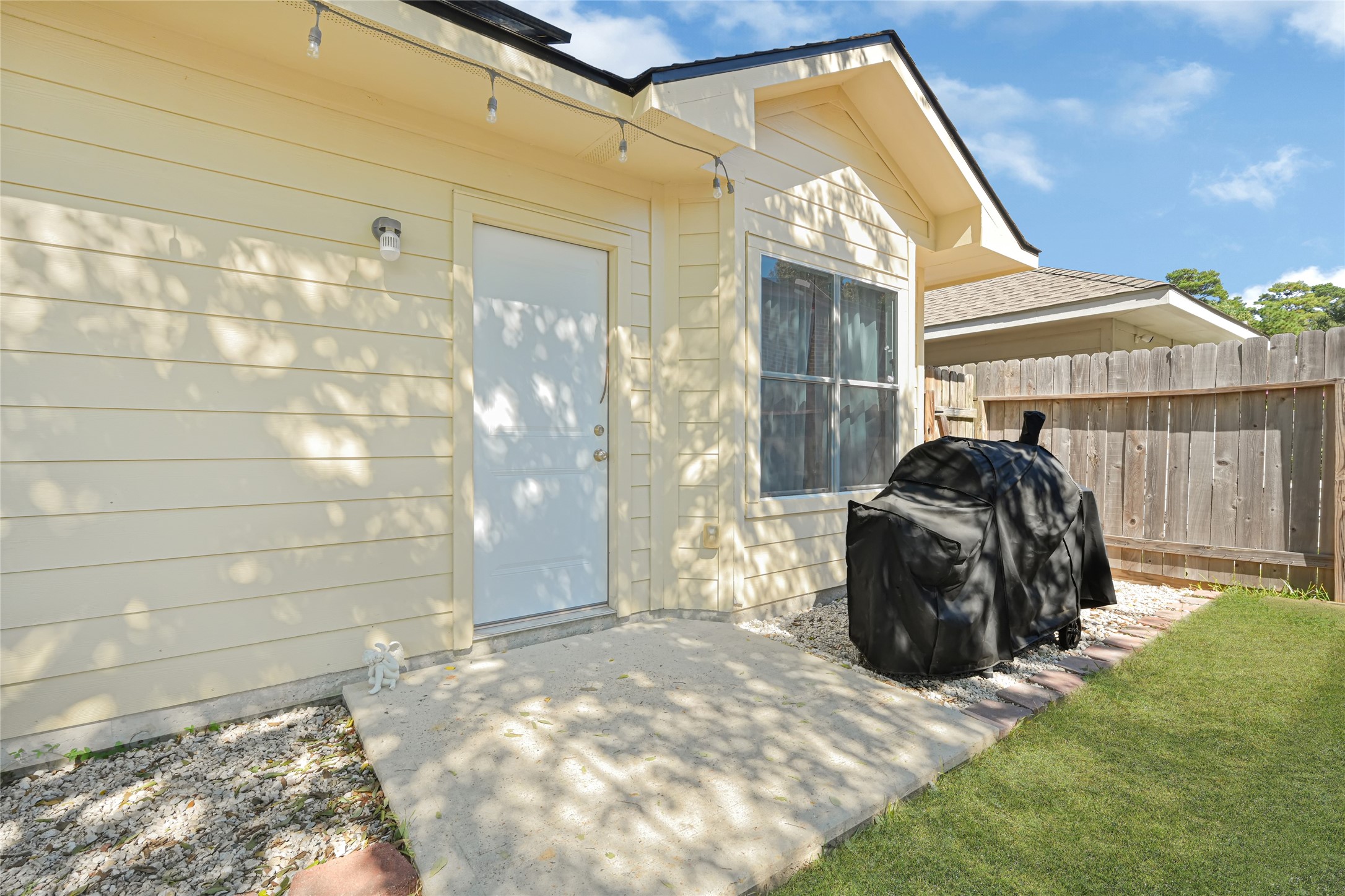 Charming backyard corner with a cozy patio area, perfect for outdoor grilling and relaxation, enhanced by a privacy fence and well-maintained lawn.