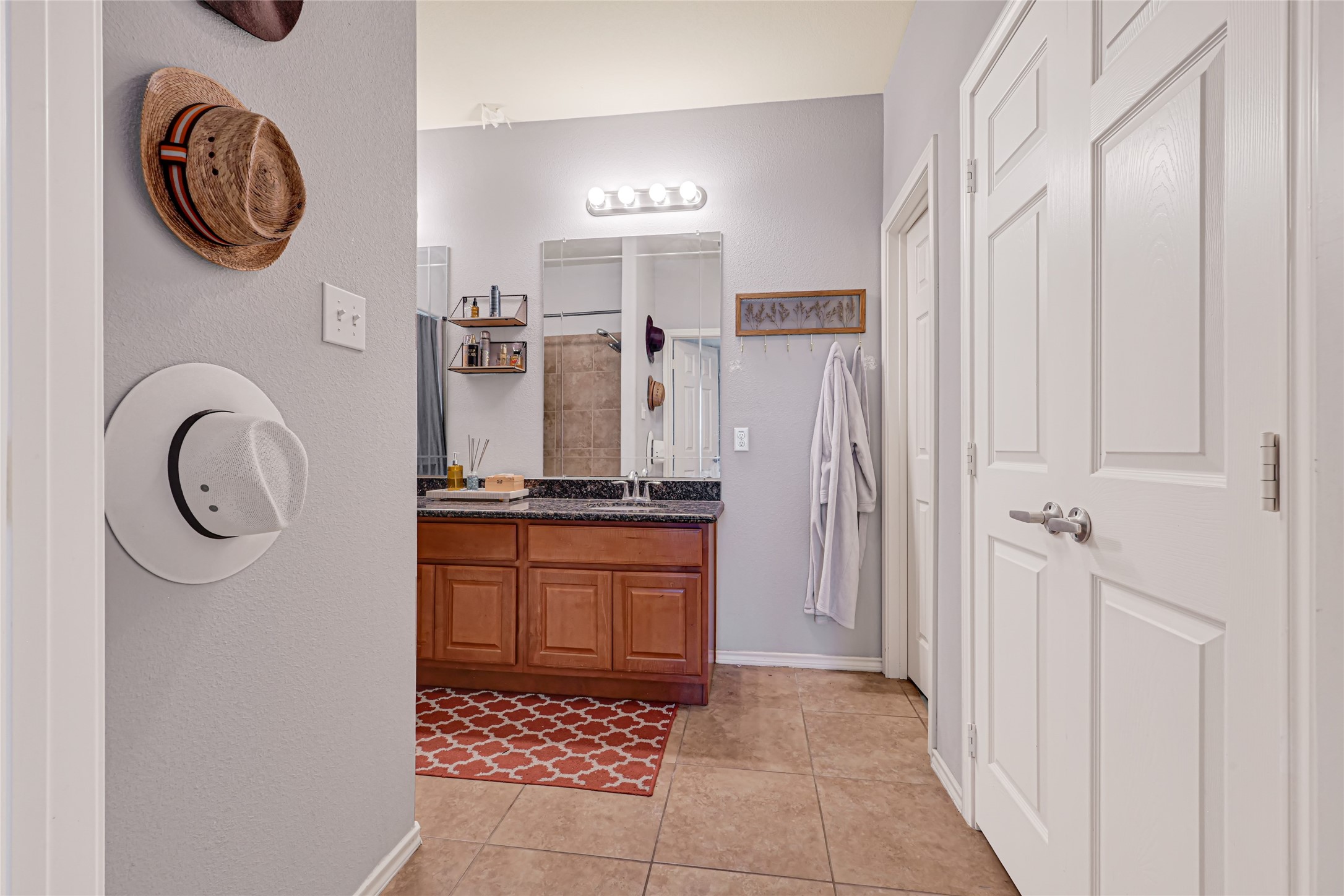 Charming bathroom with a dual-sink vanity and elegant granite countertops, complemented by warm wood cabinetry and stylish tile flooring.