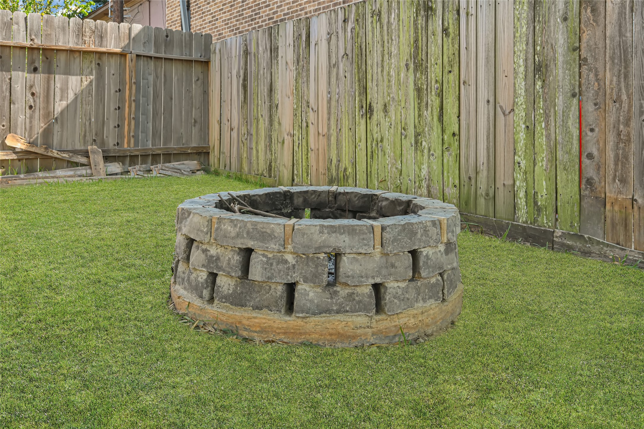 Charming backyard with a rustic stone fire pit, perfect for cozy outdoor gatherings.