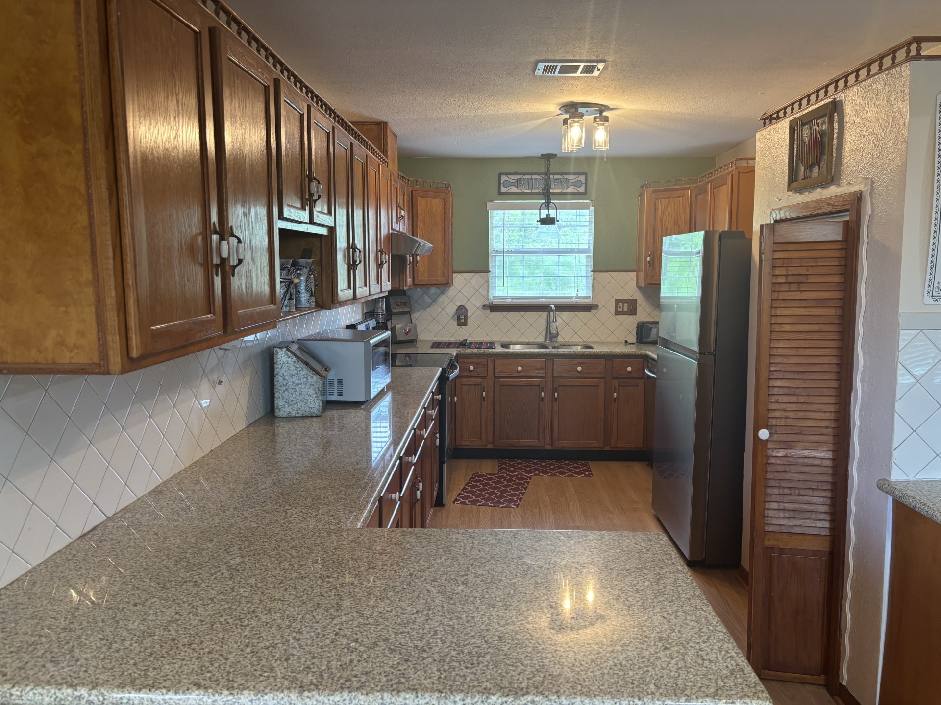 The kitchen boasts elegant wood cabinets, sleek granite countertops, and stylish wood-like flooring. The kitchen boasts elegant wood cabinets, sleek granite countertops, and stylish wood-like flooring.