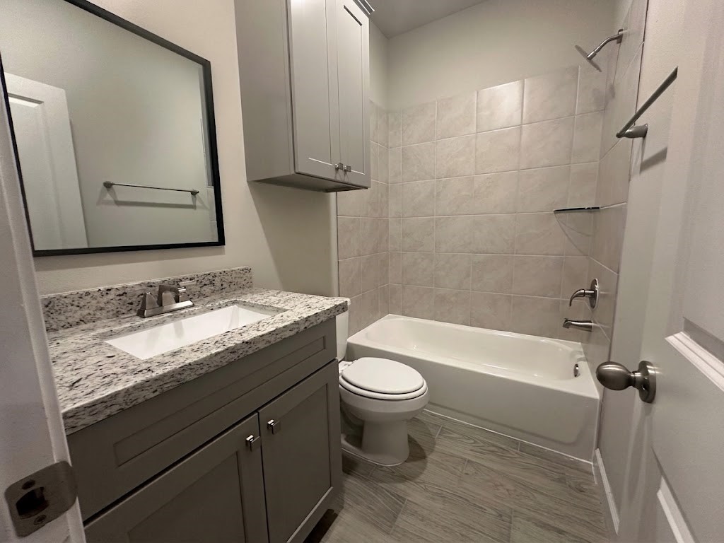 Bright secondary bathroom showcasing contemporary finishes, sleek stone vanity, and neutral tilework.