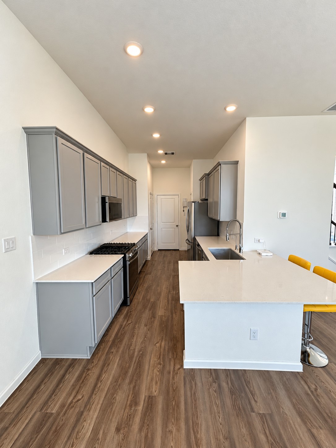 4. Kitchen with gray cabinetry, stainless steel appliances, and an island with seating. 4. Kitchen with gray cabinetry, stainless steel appliances, and an island with seating.