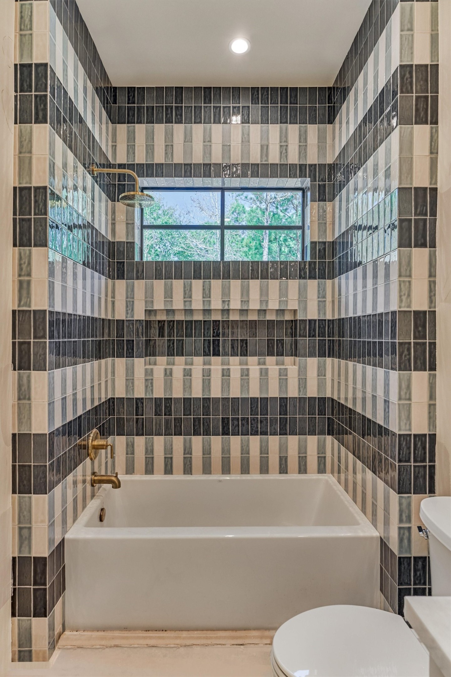 This space reflects a calm elevated design, featuring carefully selected tile in layered color and pattern. This shower/ tub combo is a dedicated space to a secondary bedroom.