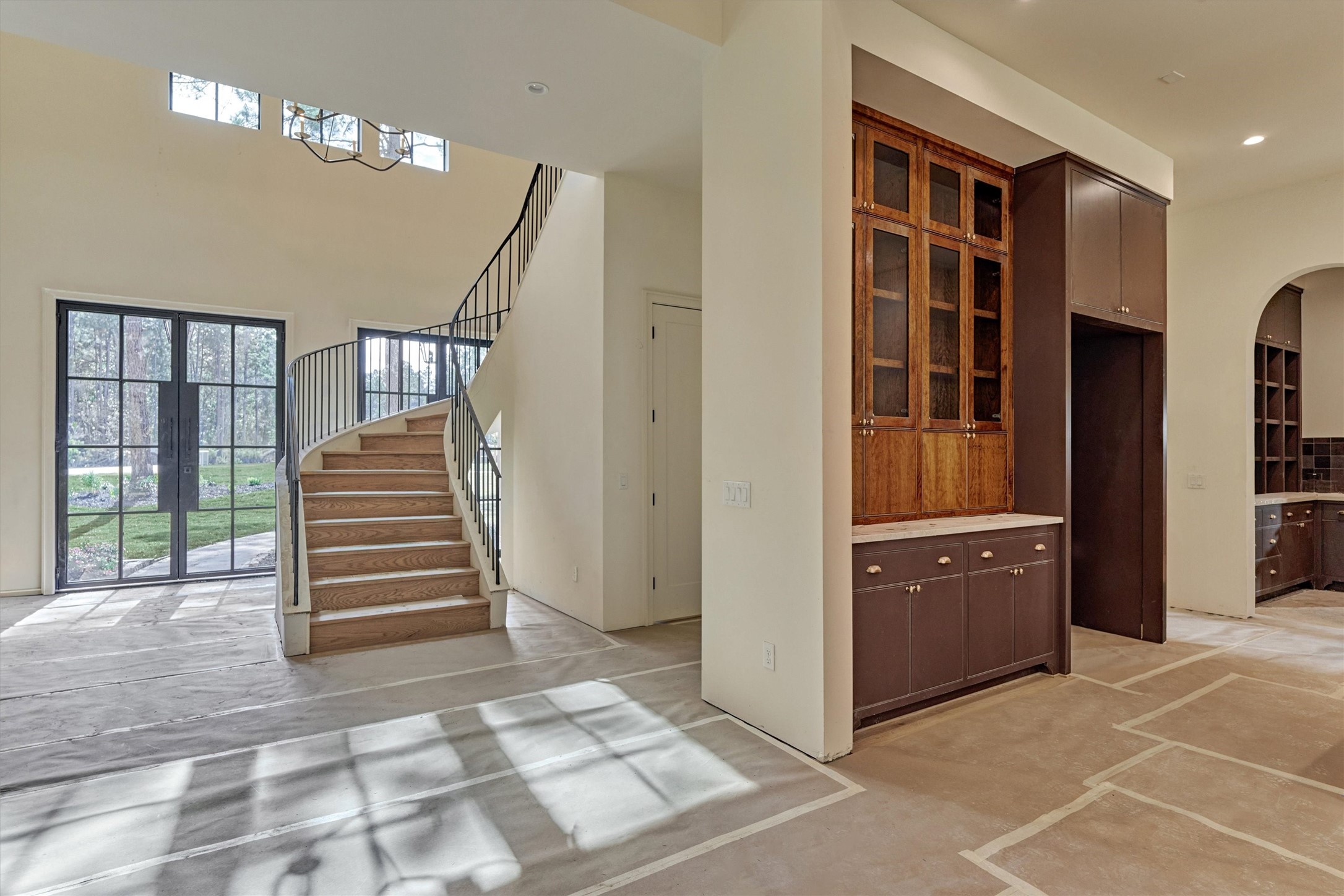 Perspective of the grand entry as it transitions into the expansive living area and the heart of the home (The Kitchen).  Thoughtful architectural design offers a glimpse of the secondary prep kitchen beyond.