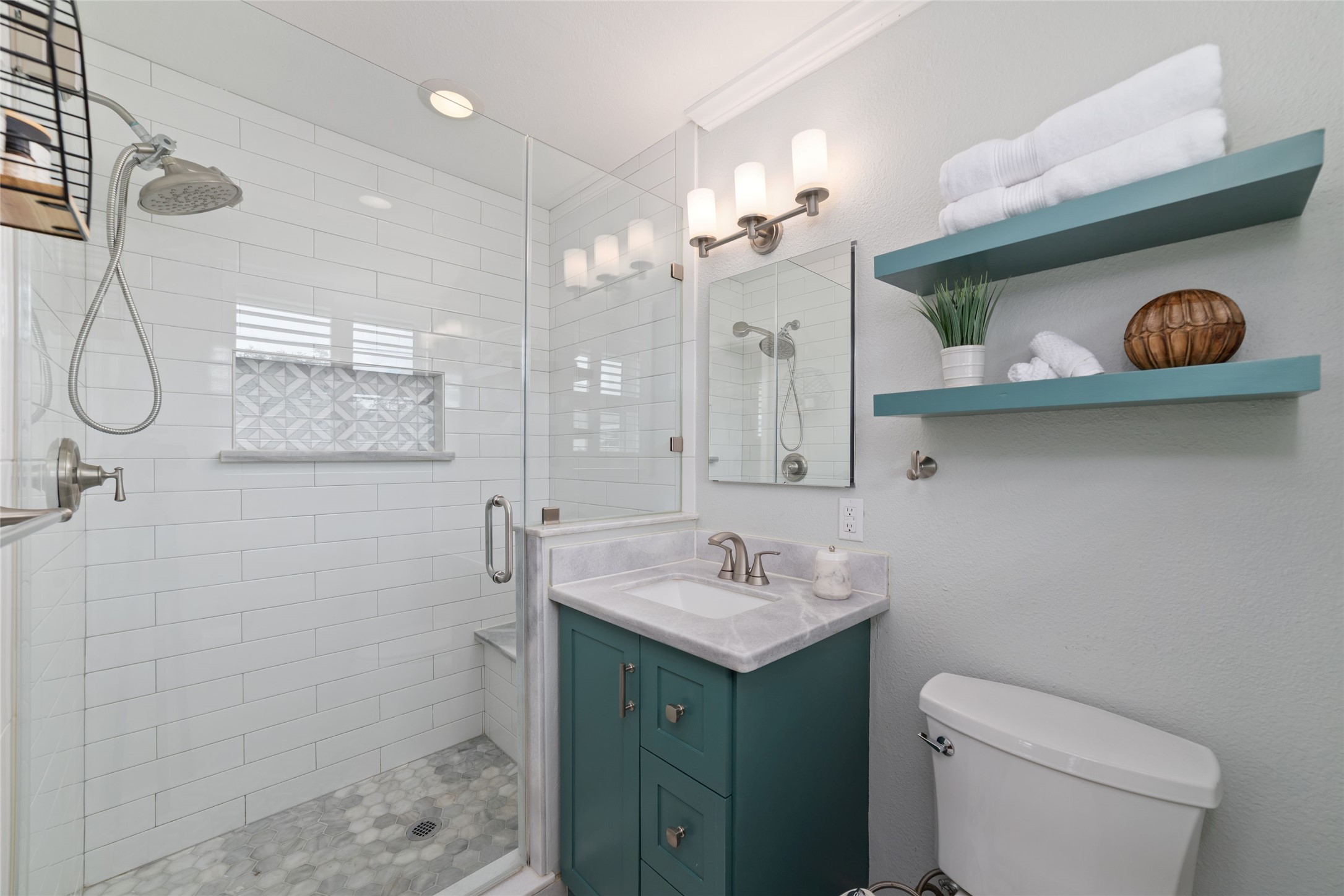 Elegant primary bath featuring a glass-enclosed shower with stylish tilework, a modern vanity and open shelving for storage.