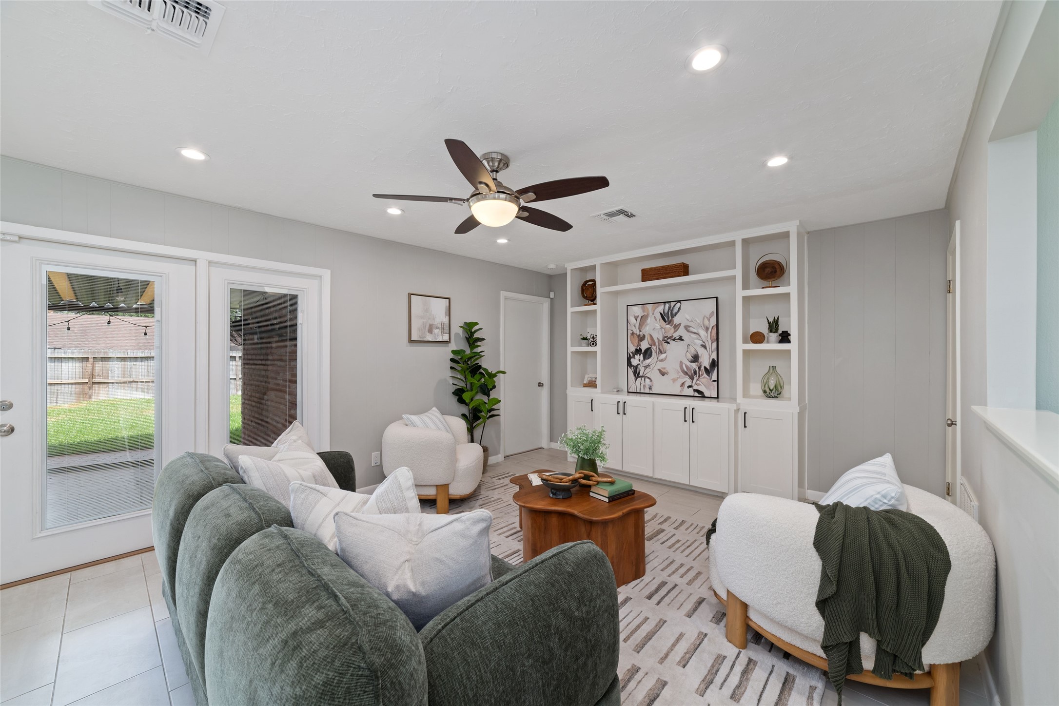 Living room includes a built-in entertainment center and French doors that open to a spacious backyard, offering a seamless indoor-outdoor flow.