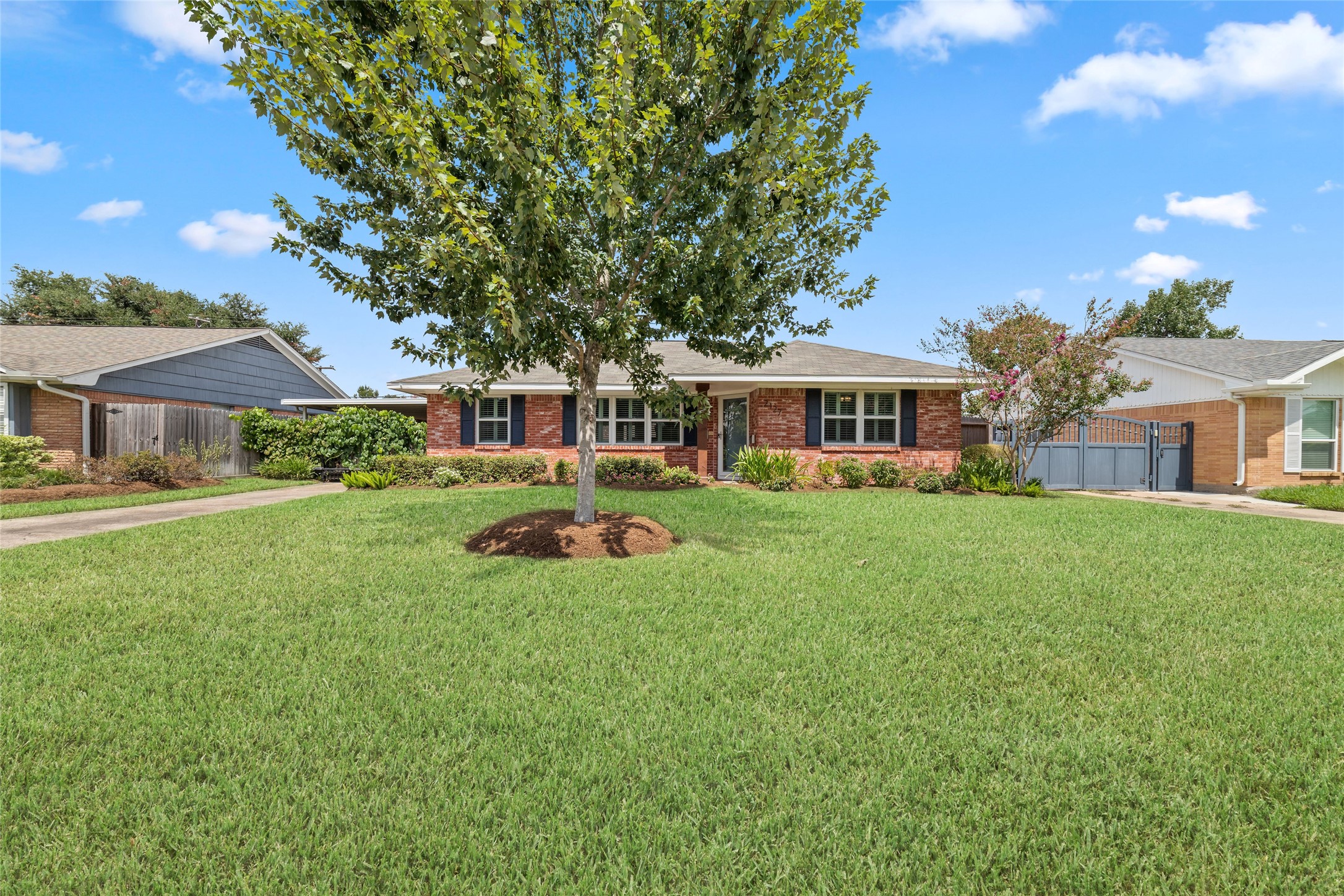 Charming brick ranch-style home with a spacious front yard and mature tree, offering great curb appeal