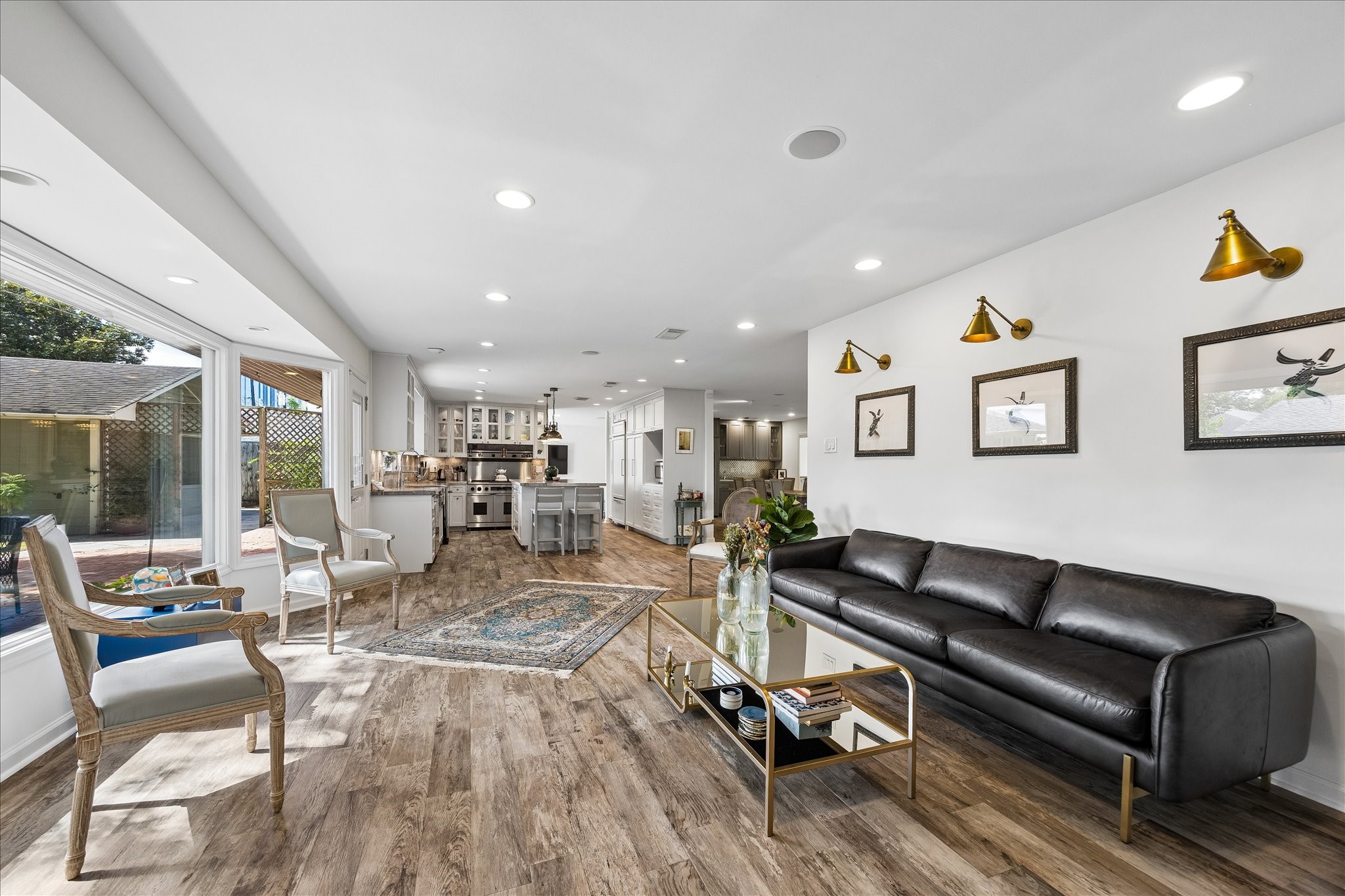 Living area flows seamlessly into the updated kitchen, creating a wonderful open-concept layout. Expansive windows, wood flooring & recessed lighting enhance this inviting space, ideal for everyday living & entertaining.
