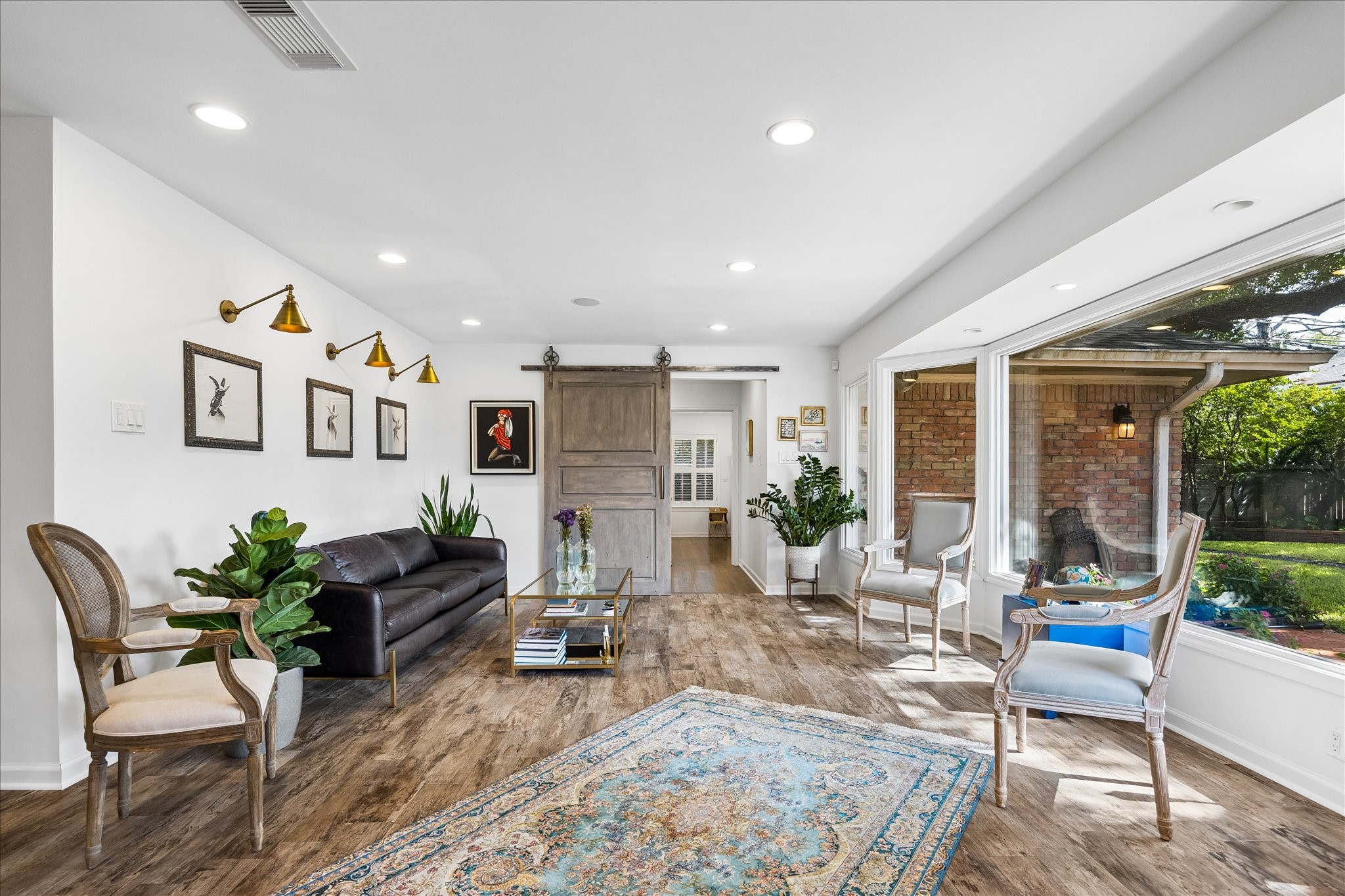 Bright & inviting living area features wood flooring, recessed lighting, decorative wall sconces & a sliding barn door. Large windows bring in natural light & offer beautiful views of the backyard.