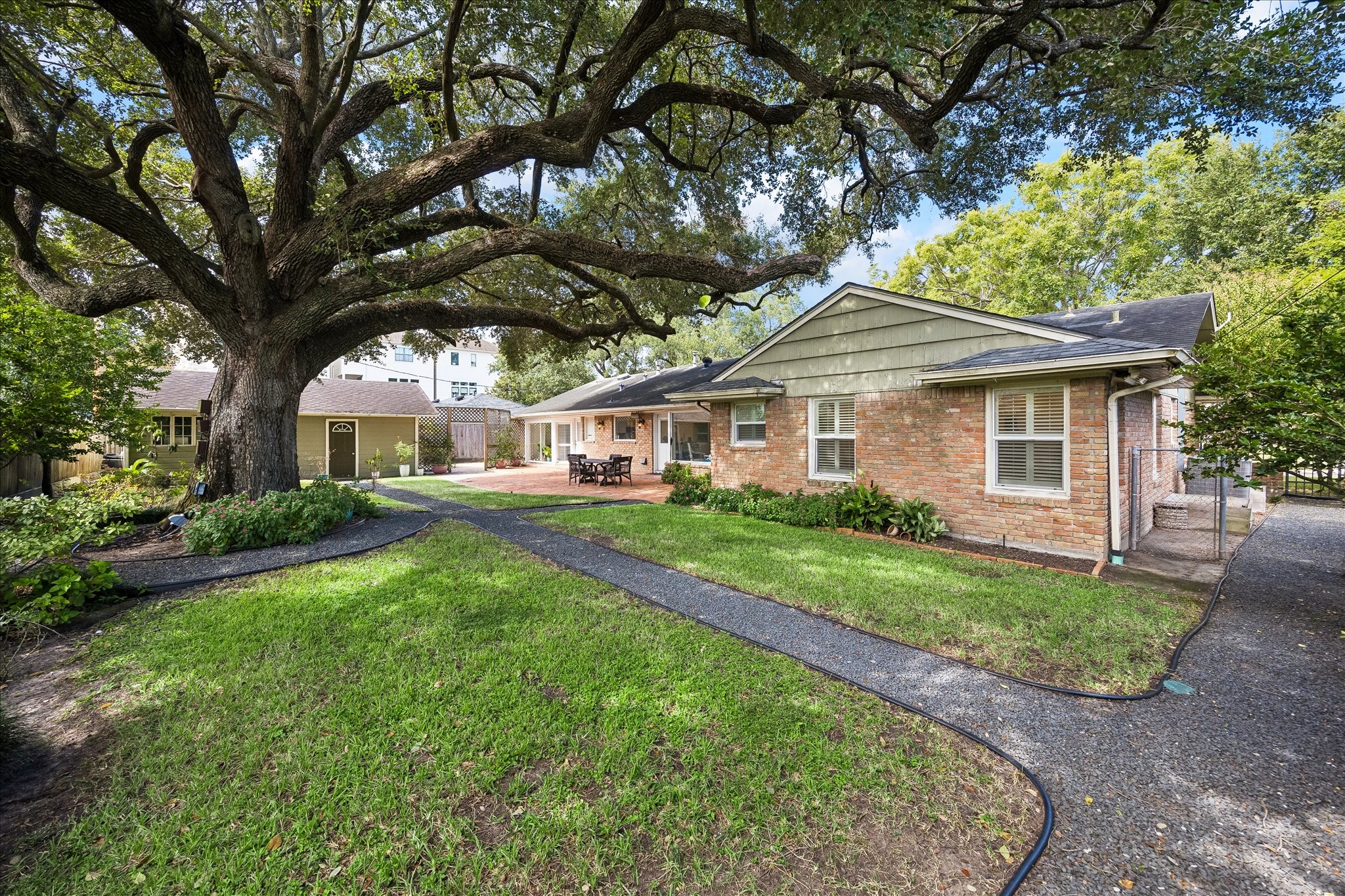 Rear exterior showcases the home's classic brick faade, expansive lawn & established landscaping. Winding pathways connect the outdoor spaces, while the detached 2-car garage offers convenient parking & additional storage possibilities.