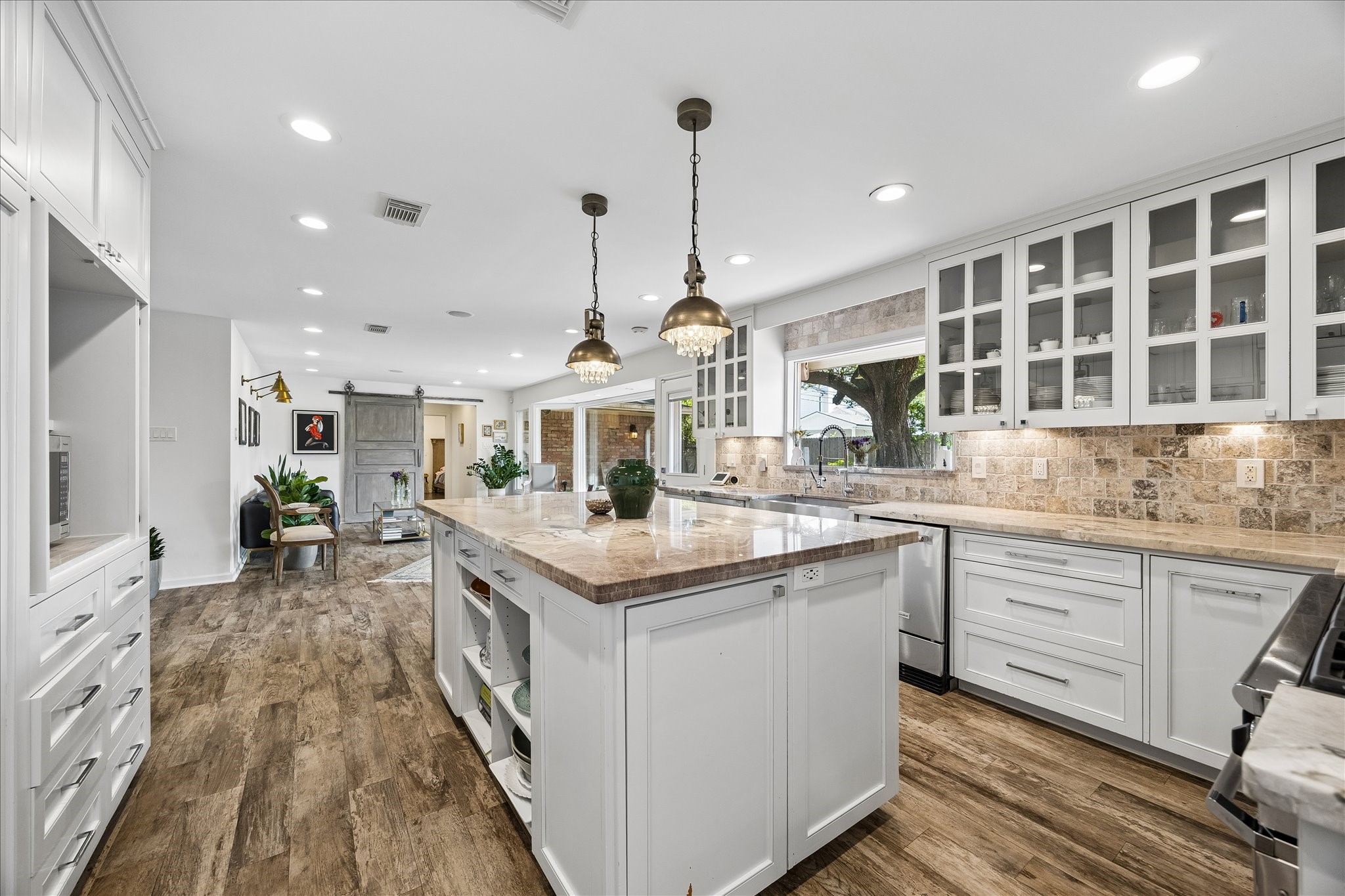 Expansive kitchen showcases an oversized island w/stone countertop, extensive cabinetry, under-cabinet lighting & wood flooring. Open layout flows seamlessly into the adjoining living area, ideal for entertaining.