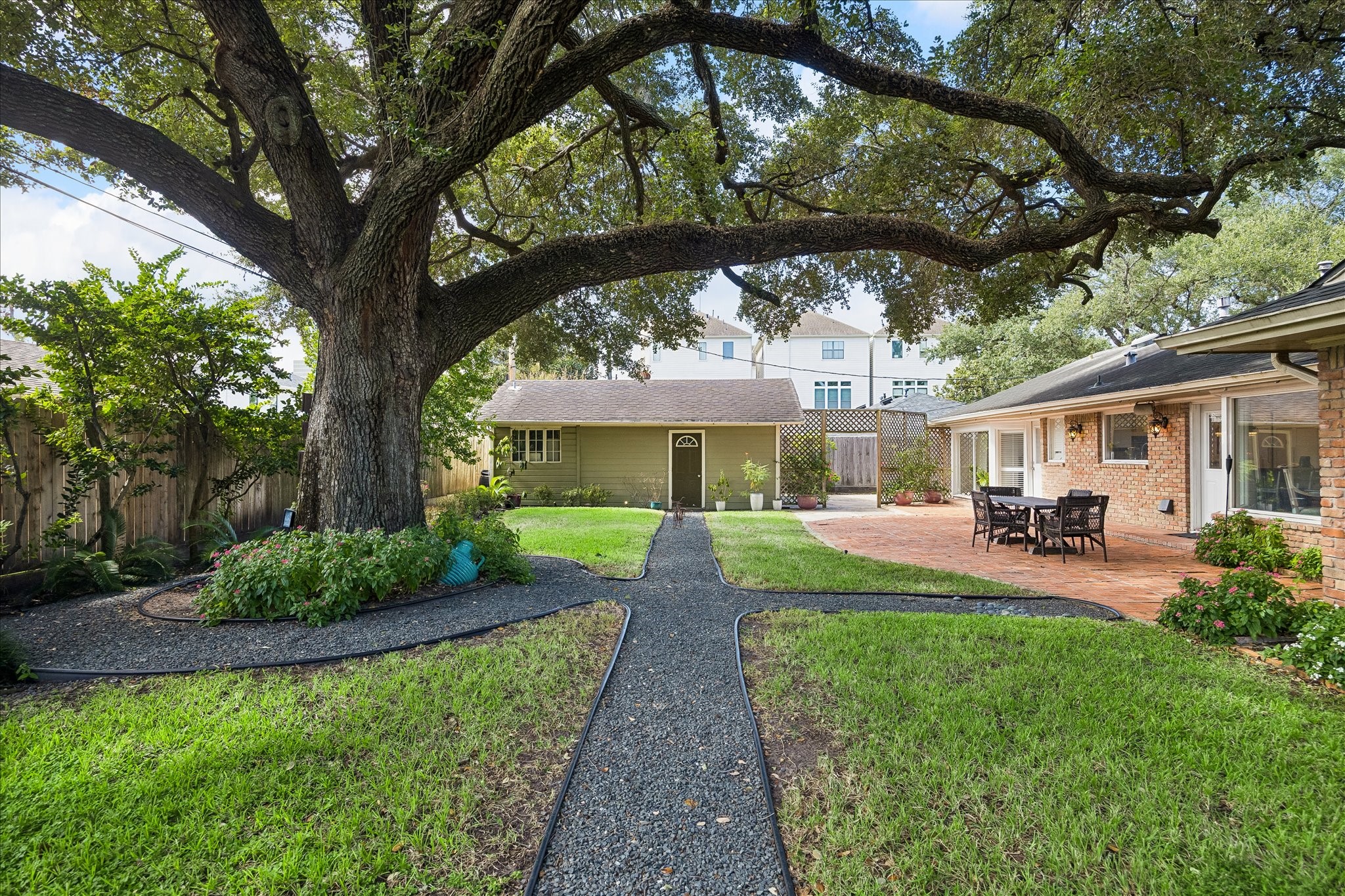Beautiful backyard features a magnificent mature oak tree as its centerpiece, surrounded by landscaped garden beds & winding pathways. The expansive brick patio connects to the home, offering an ideal setting for outdoor gatherings.