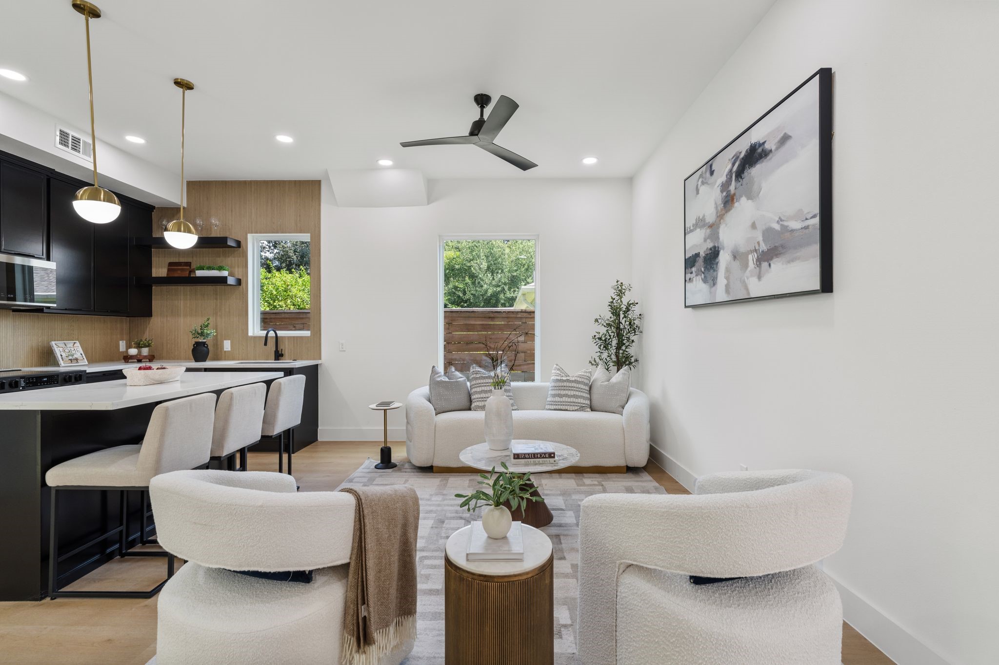 Bright and spacious open-concept living area featuring a modern kitchen with sleek cabinetry,cozy seating, and large windows that invite natural light, perfect for entertaining or relaxing.